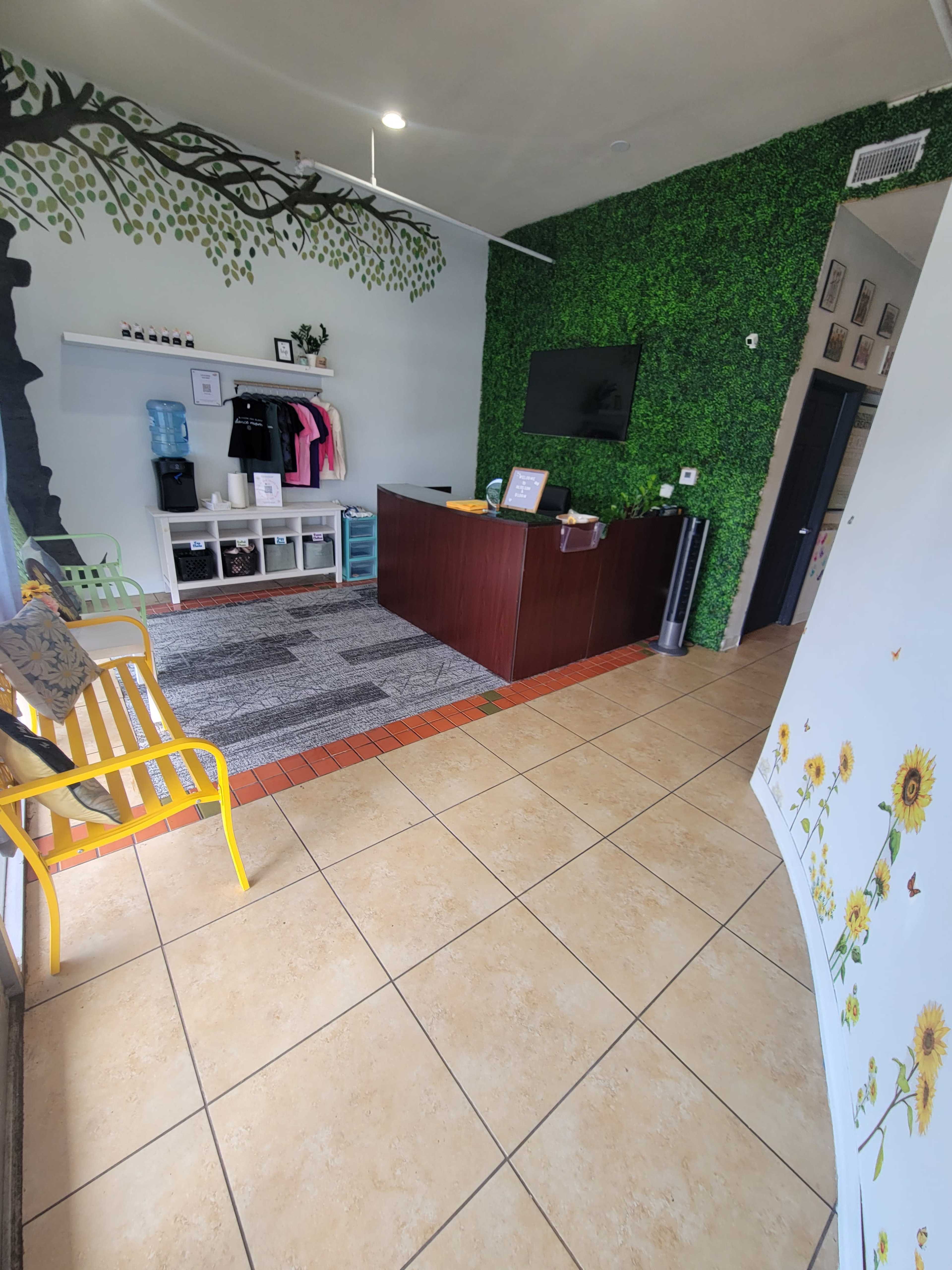 The image showcases a reception area featuring a wooden desk, green wall decor, and clothing displayed on shelves.