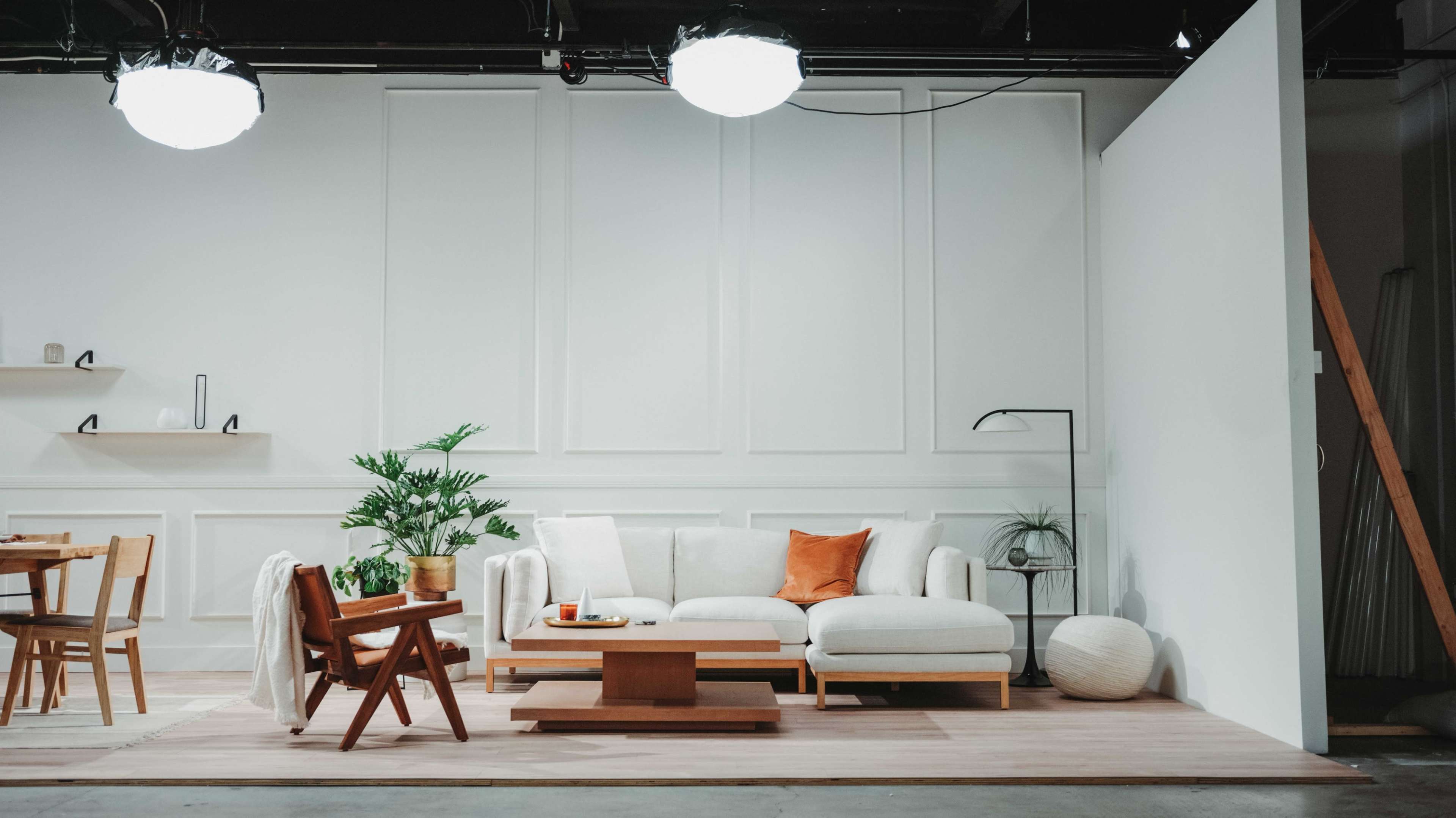A modern living room setup with a white couch, wooden coffee table, and a dining area featuring a wooden table and chairs.