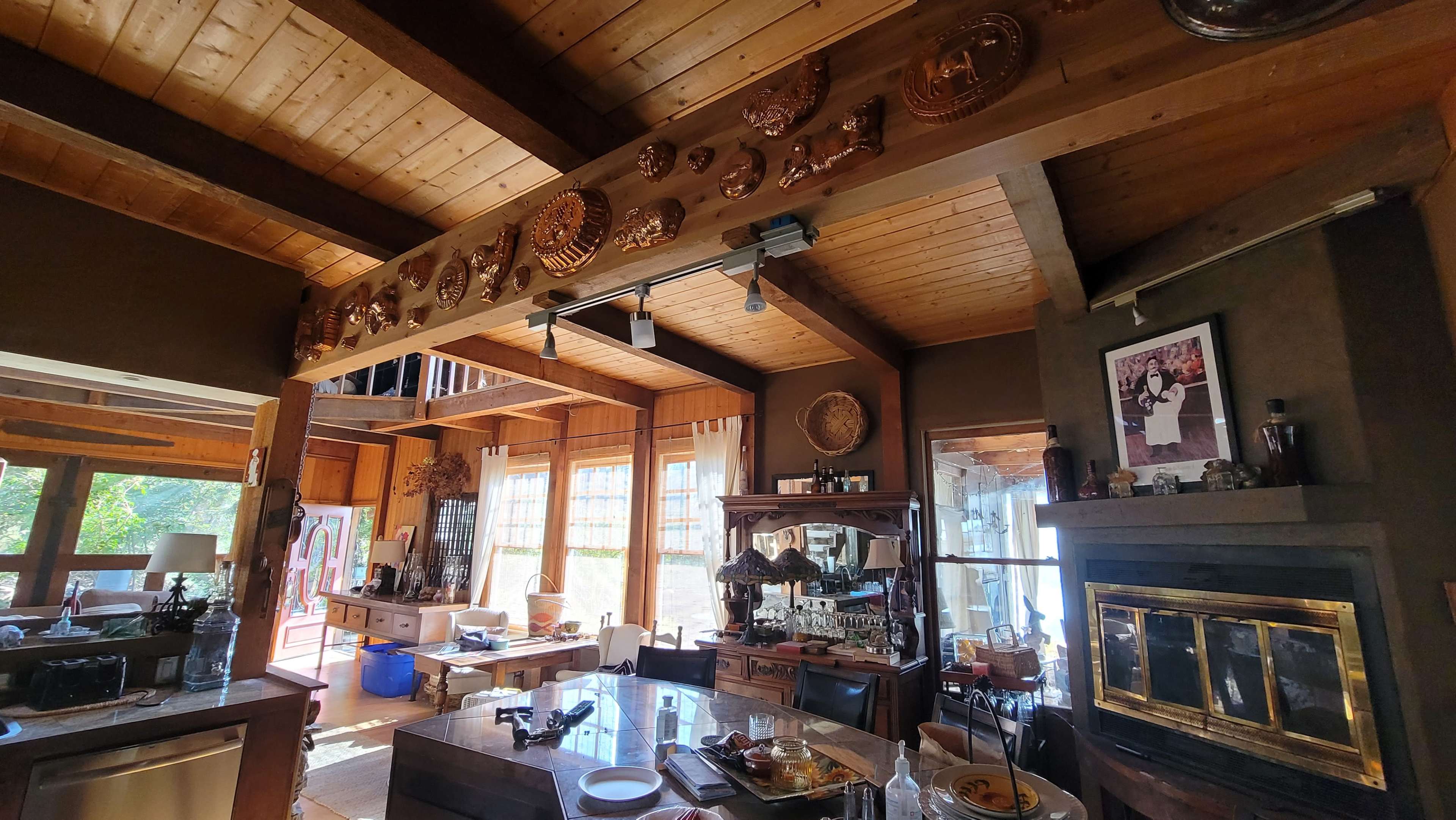 A cozy interior room with wooden beams, a fireplace, and various decorative items on display.