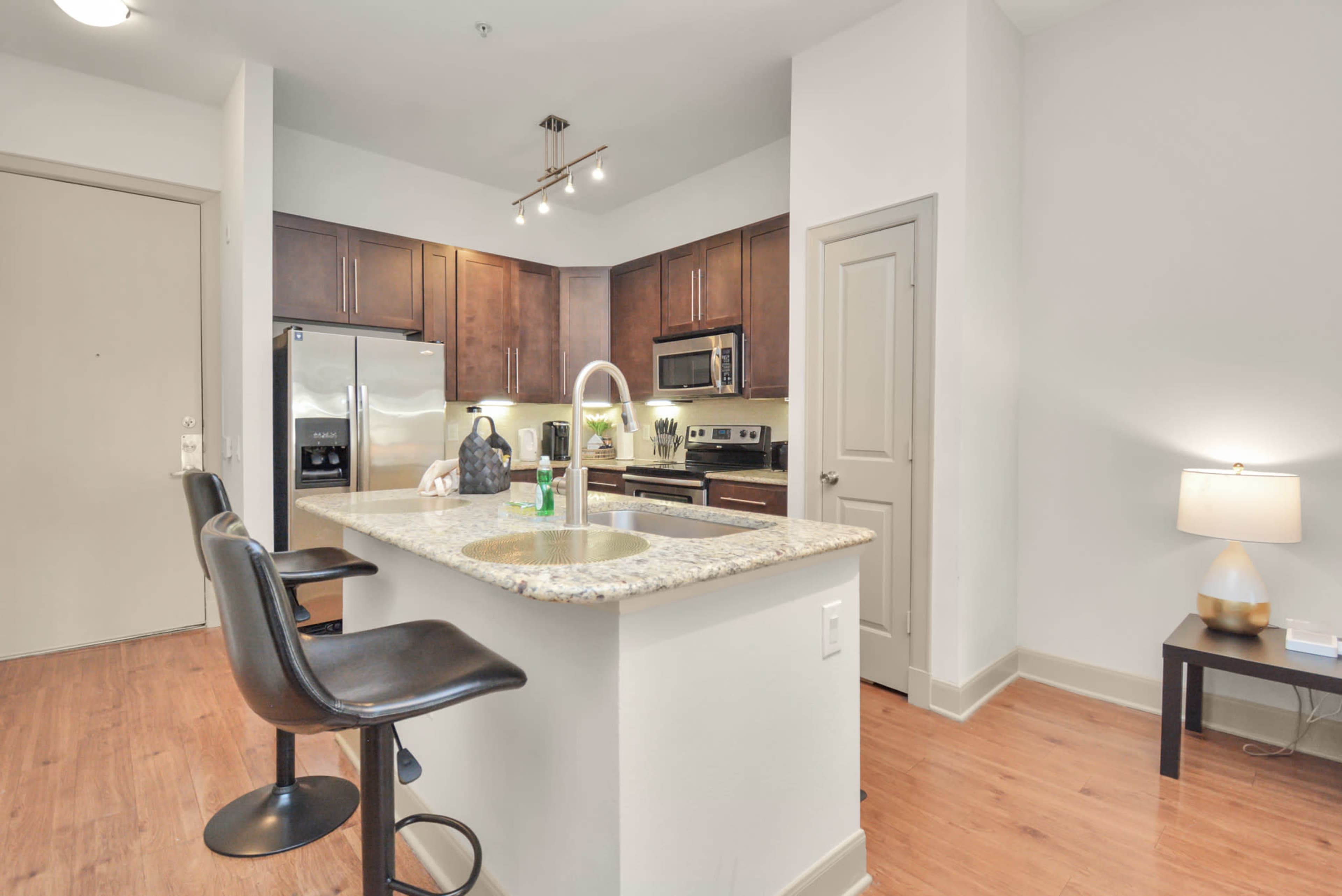 A modern kitchen with dark wooden cabinets, stainless steel appliances, and a granite countertop with bar seating.