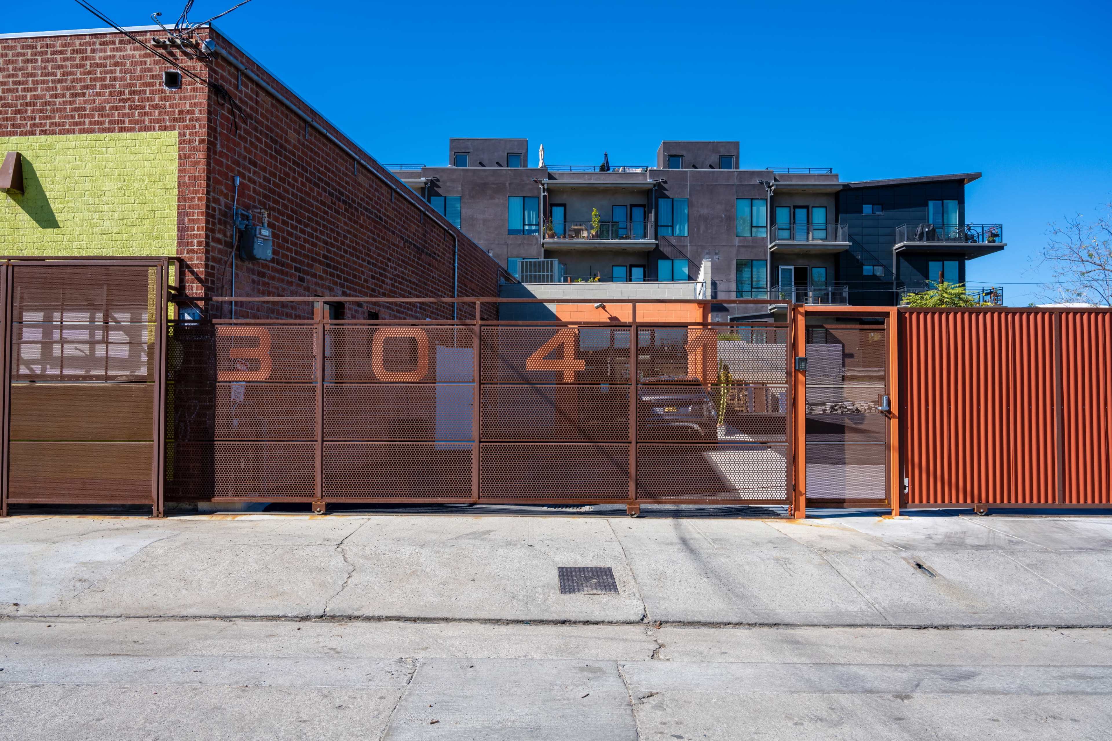 The image shows a fenced area with the number "304" prominently displayed, adjacent to a multi-story building with balconies.