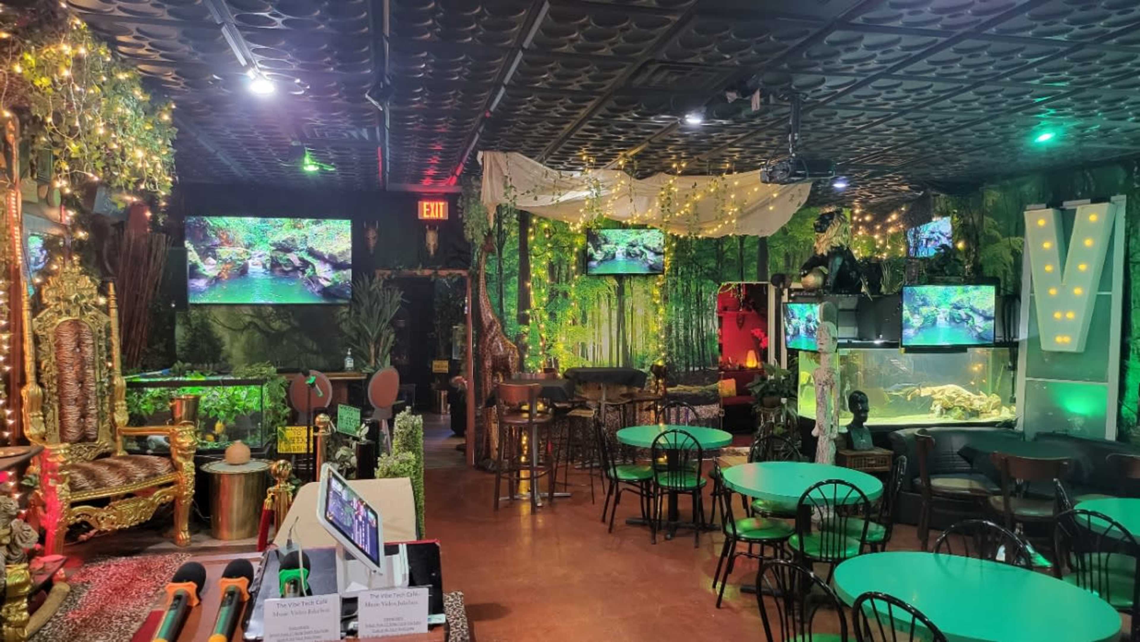 A themed restaurant interior adorned with lush greenery, ambient lighting, and multiple screens displaying nature scenes.