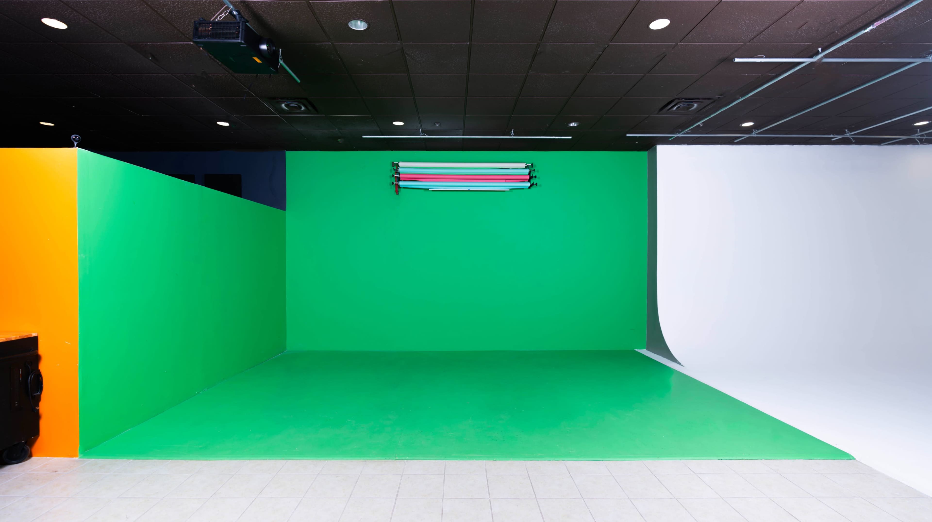 A studio space featuring green and white backdrop panels along with overhead lighting fixtures.