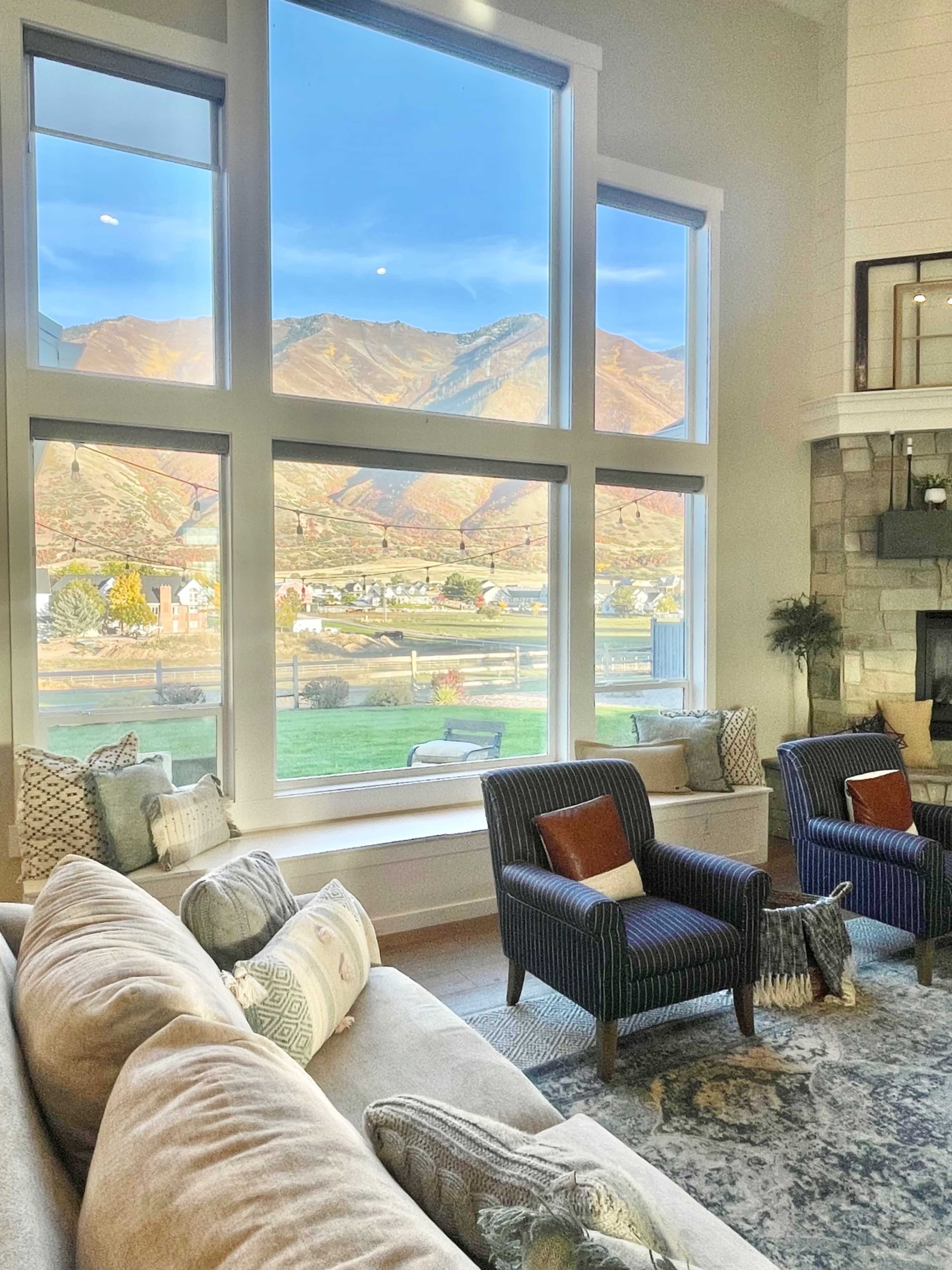 A spacious living room features large windows that showcase a panoramic view of mountains and fields outside.