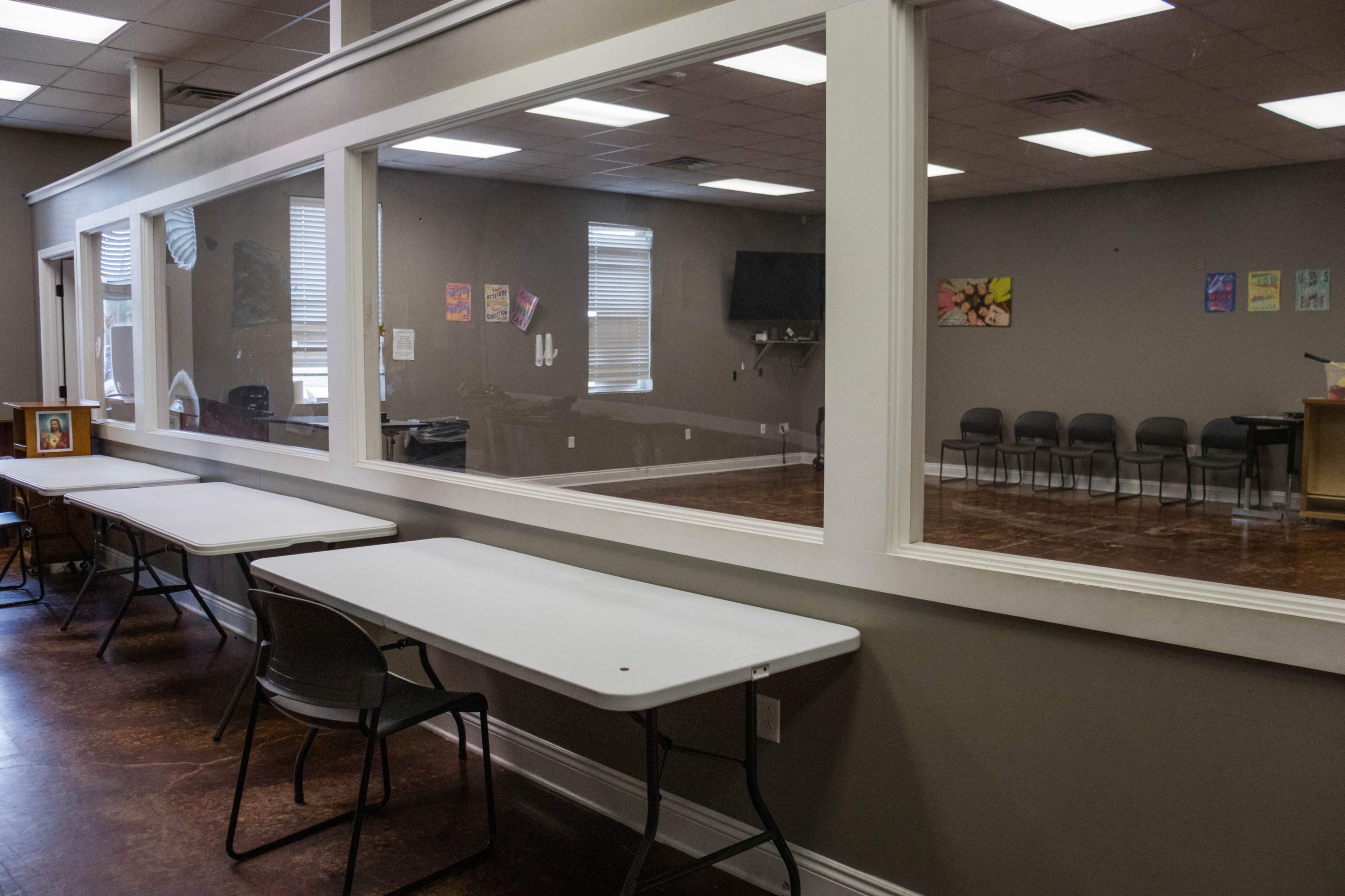 A room with a glass wall separating a seating area on one side from an empty meeting space on the other.