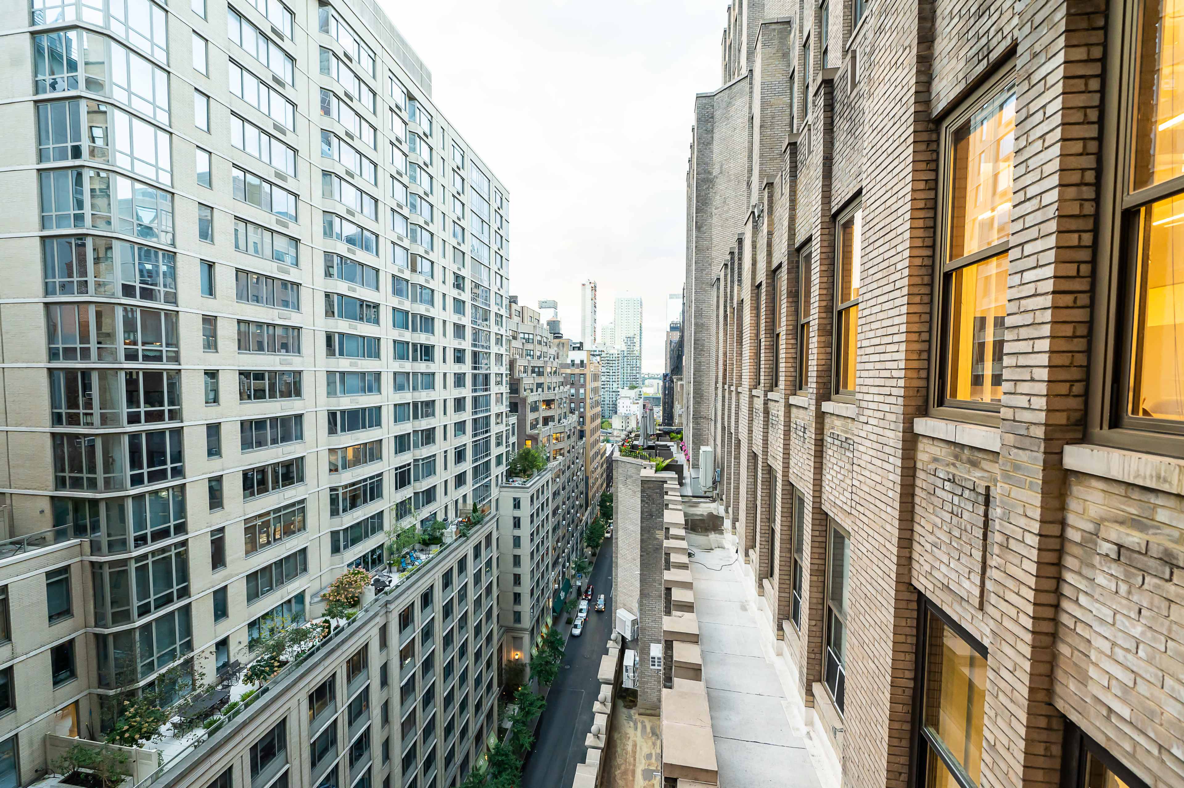 A view of two tall buildings along a city street, with one building featuring a brick facade and the other a glass exterior.