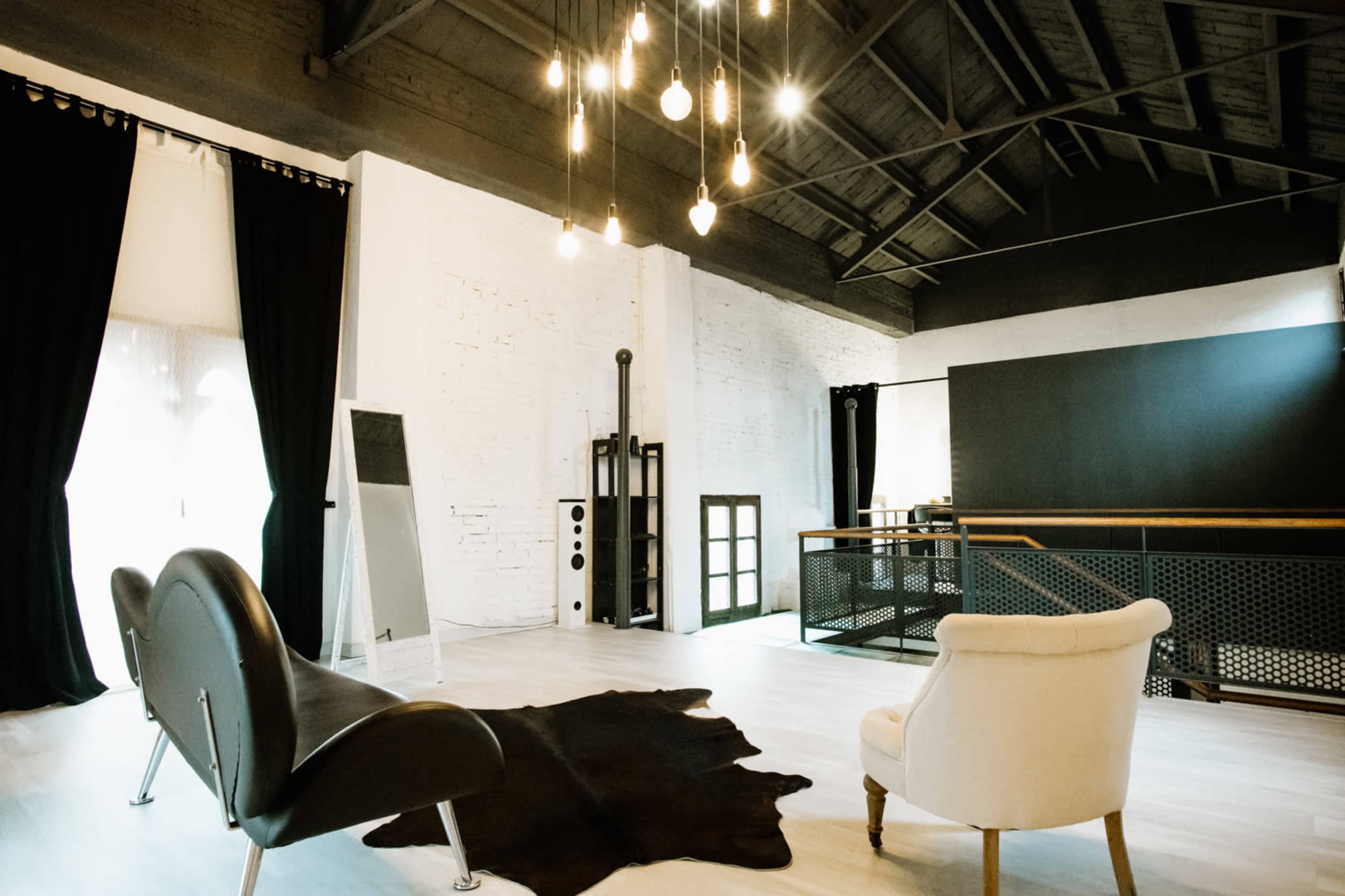The room features a black and white color scheme with a modern design, including a cowhide rug, stylish chairs, and dramatic lighting fixtures.