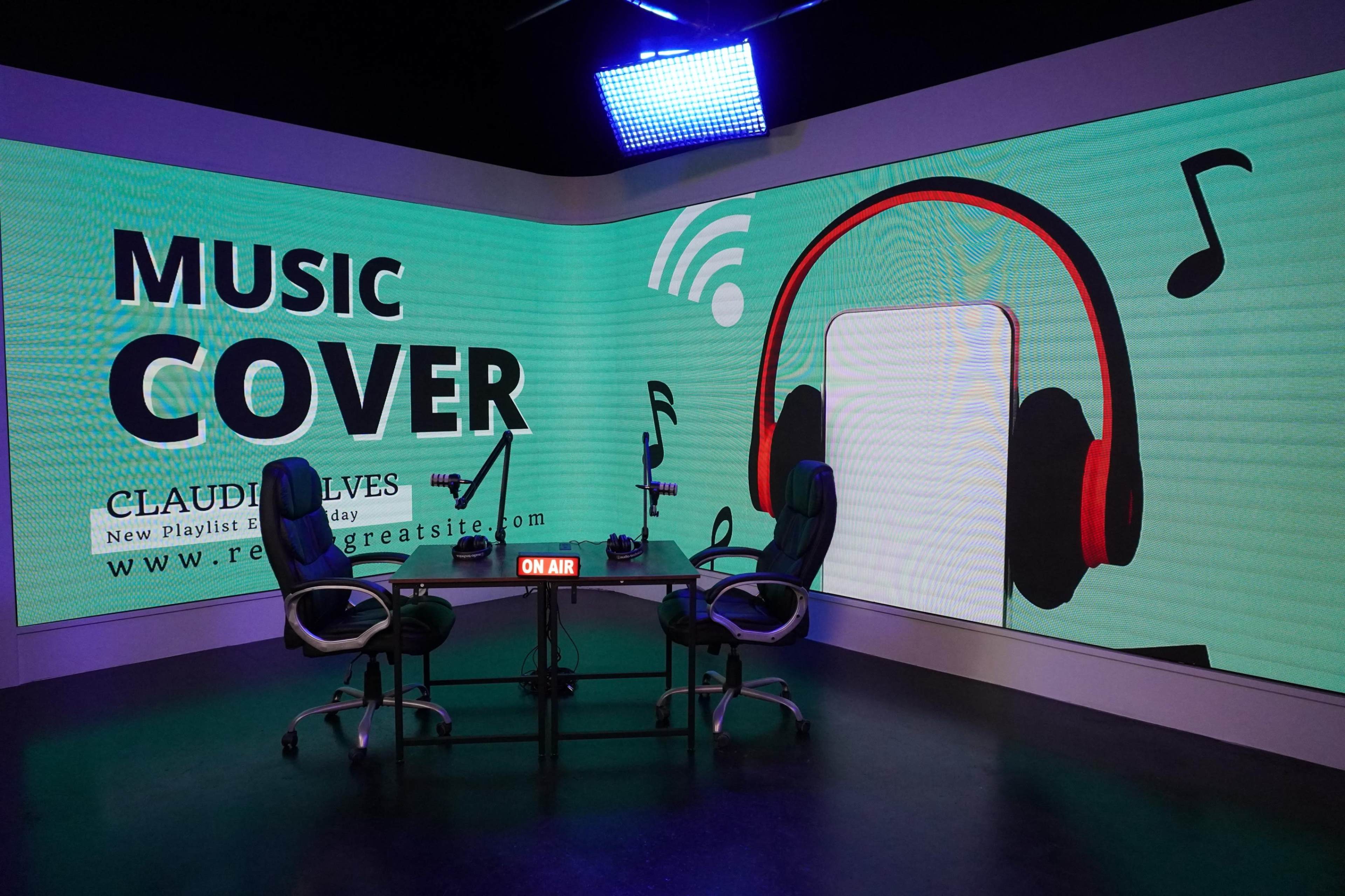 The image depicts a modern studio setup with two chairs and a large backdrop displaying text that reads "MUSIC COVER" and visual elements like musical notes and headphones.