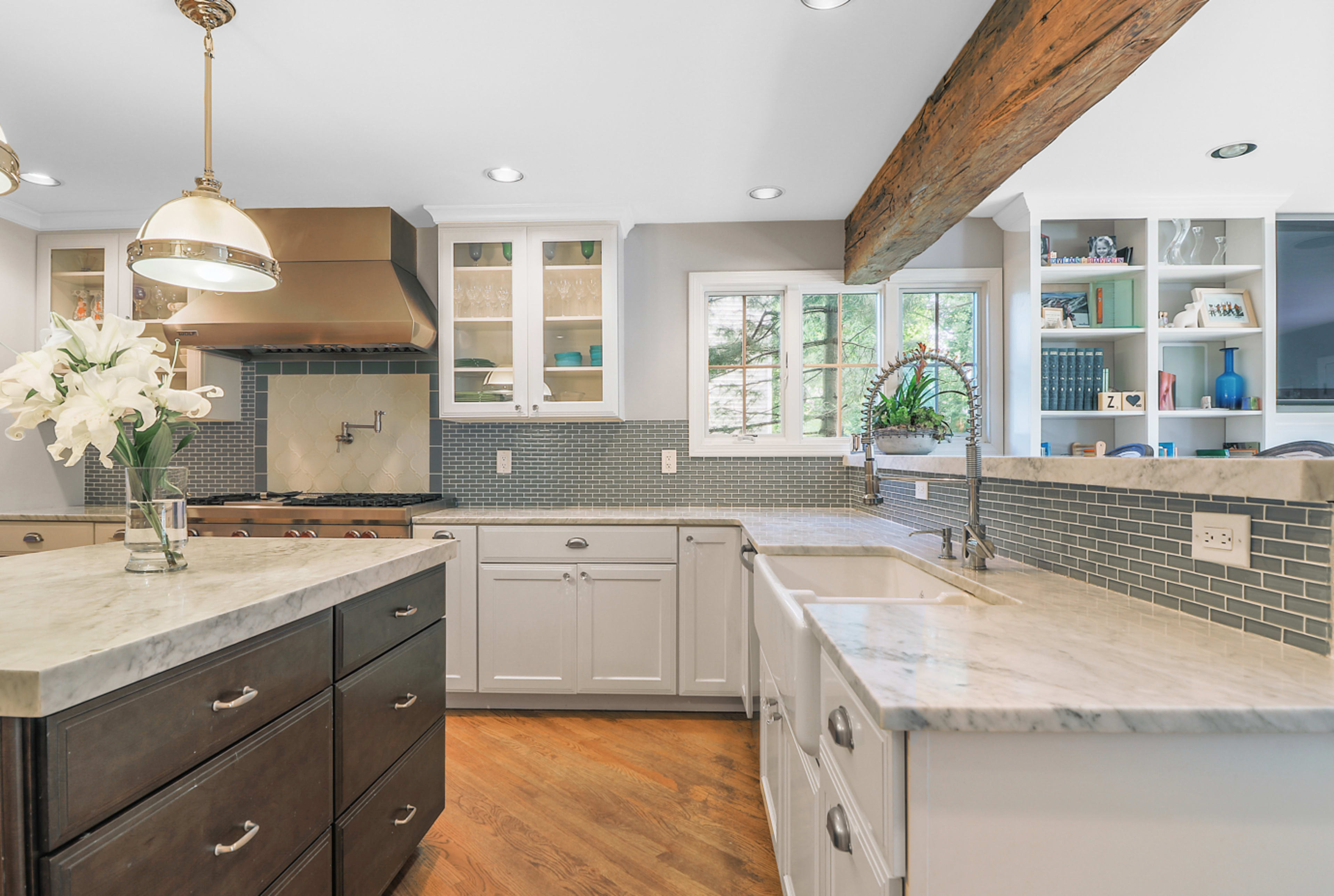 The kitchen features a large central island with a marble countertop, white cabinetry, and a tile backsplash.