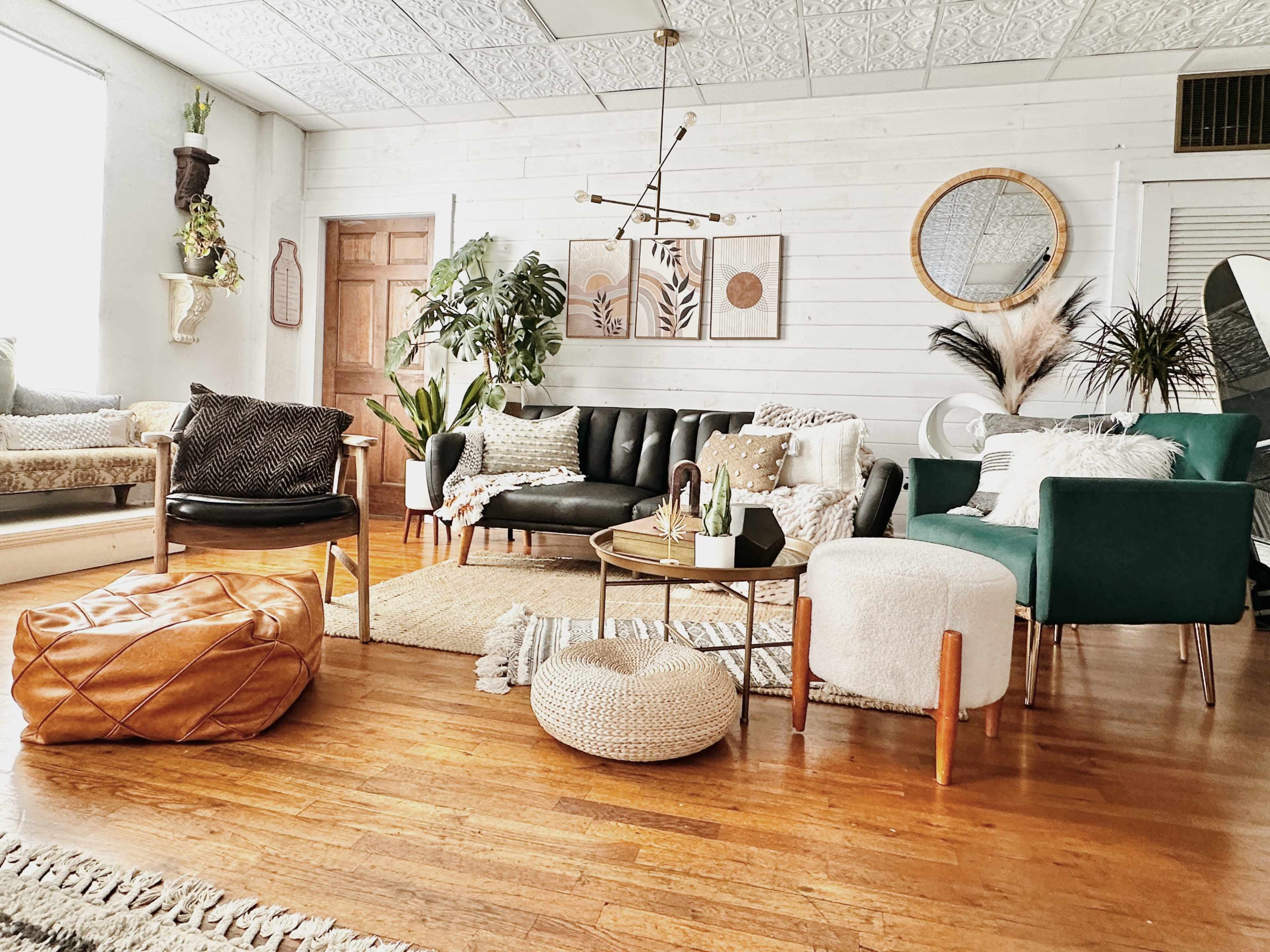 A stylish living room featuring a variety of seating options, decorative plants, and a round coffee table on a wooden floor.