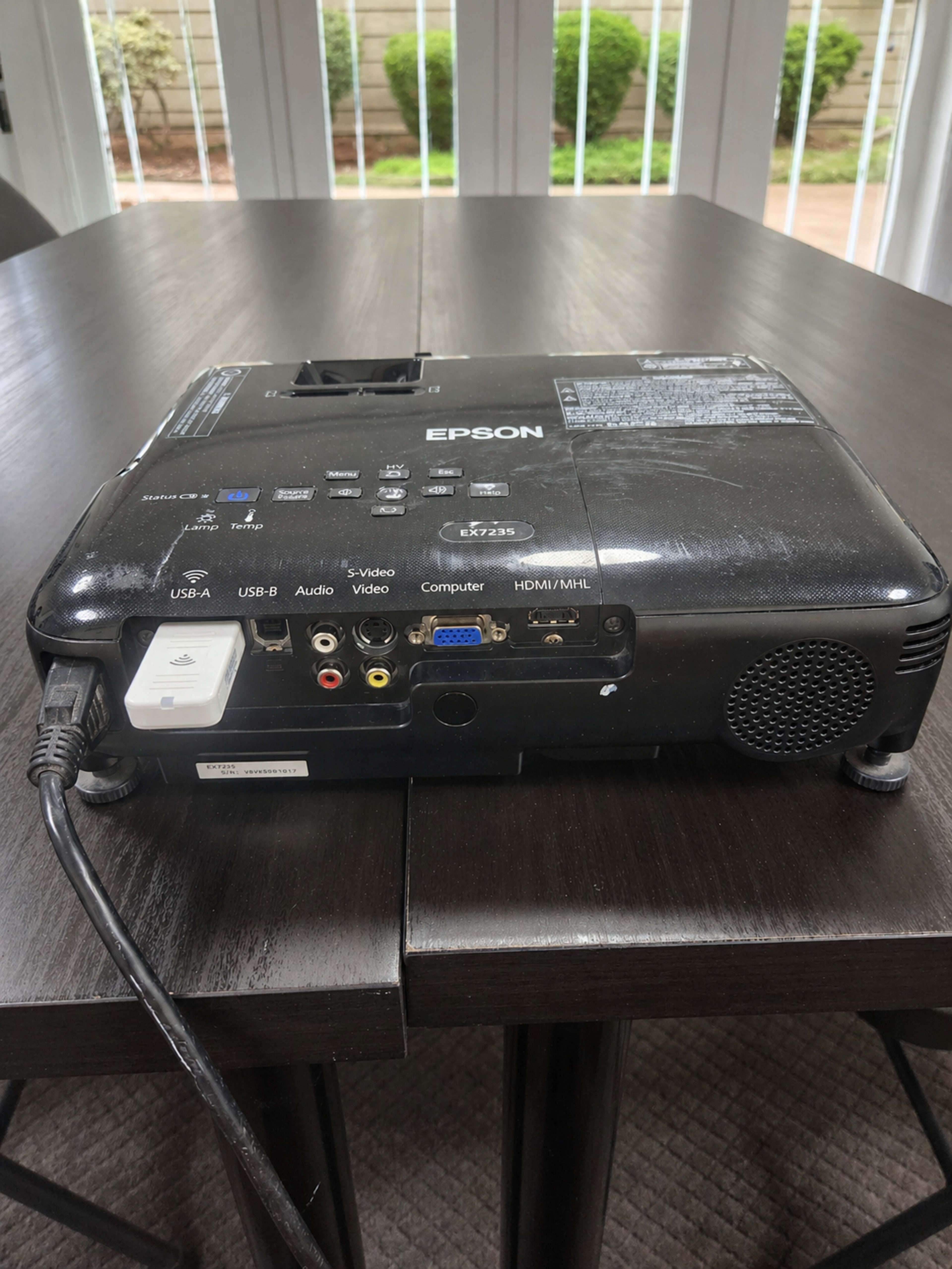 The image shows the back of an Epson projector, displaying various input ports including USB, audio, video, and HDMI connections.
