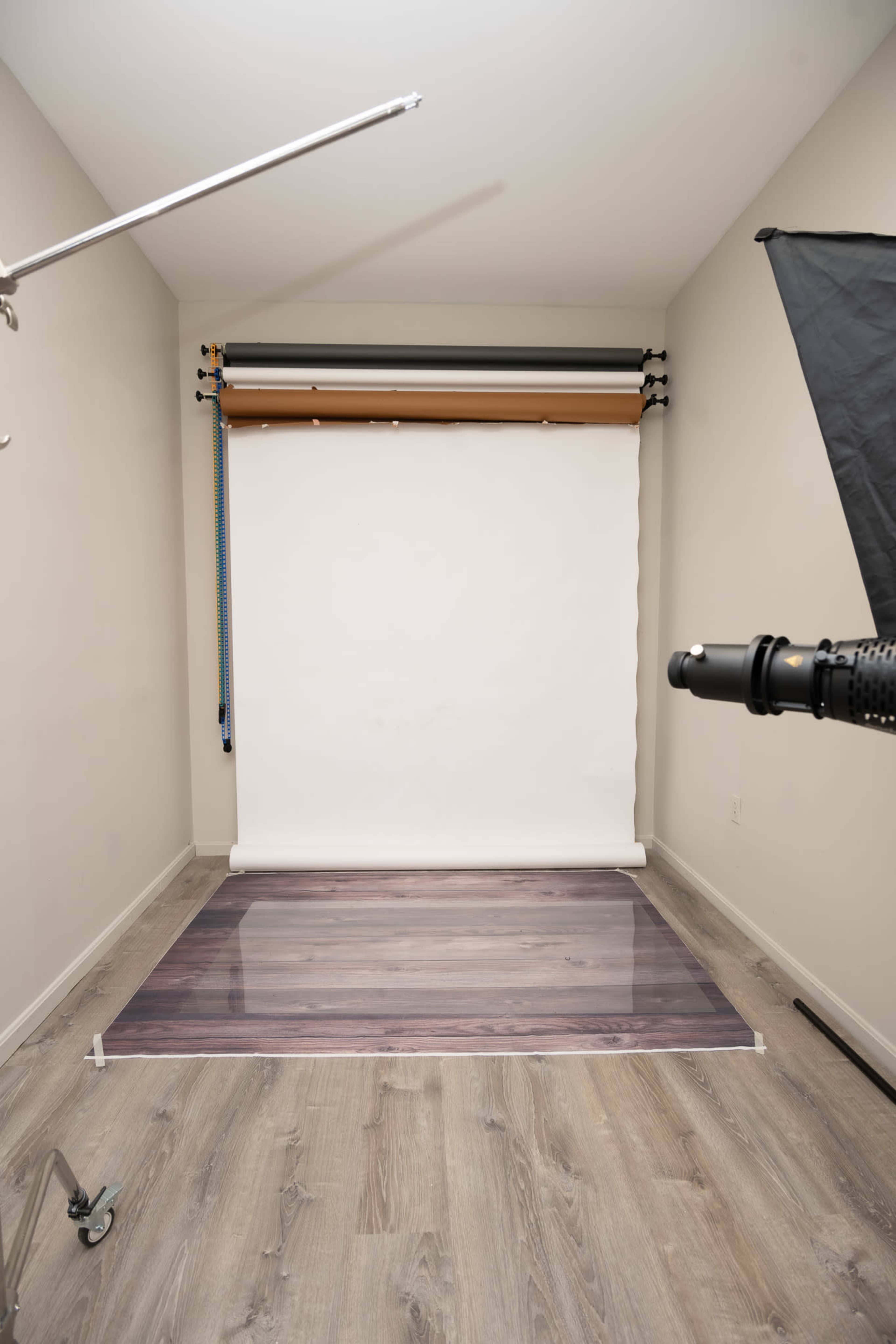 The image shows a photography studio setup featuring a seamless backdrop and a polished wooden floor.
