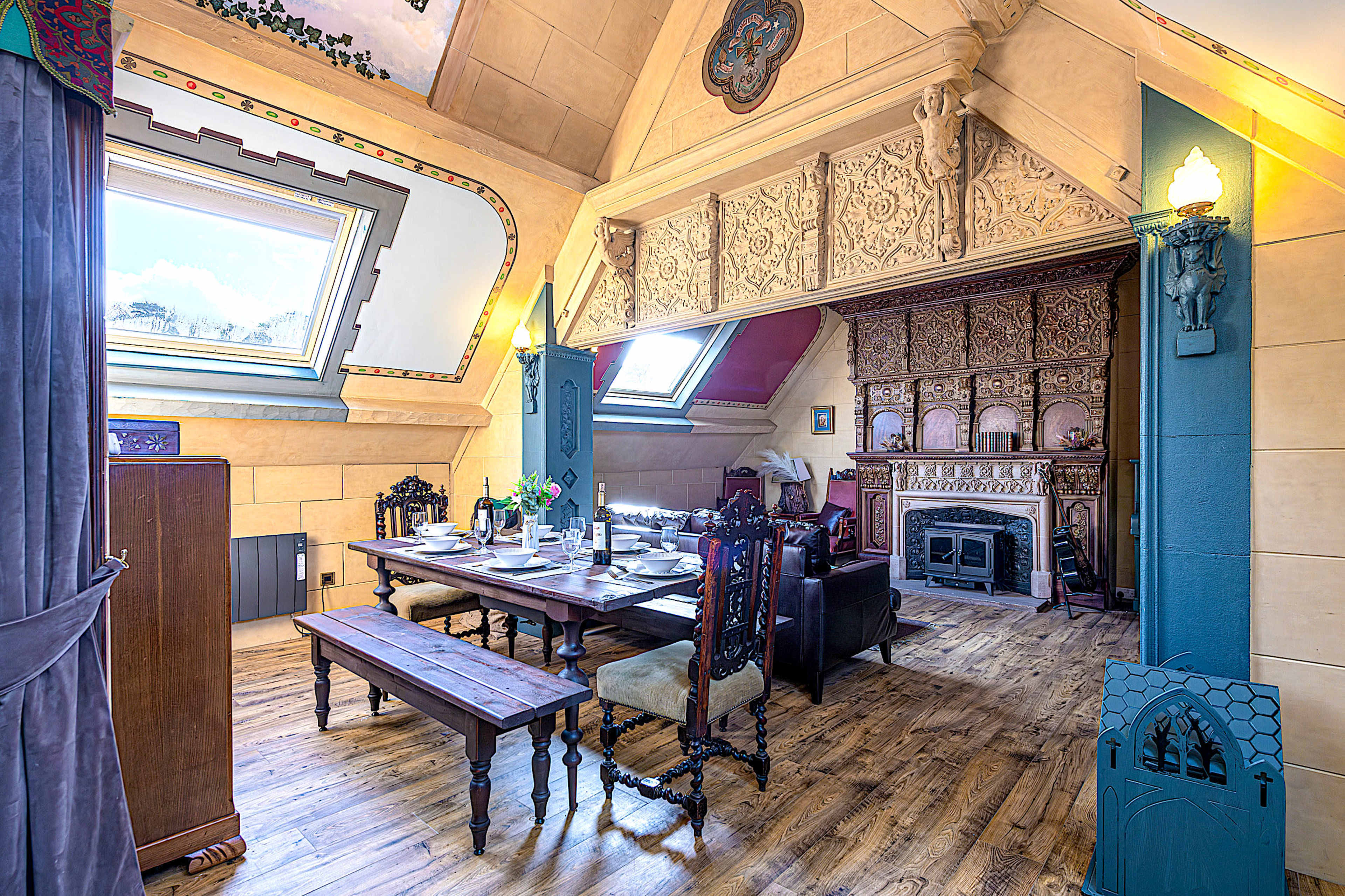 The image shows a large, intricately designed room with a wooden dining table, ornate furniture, and a decorative fireplace.