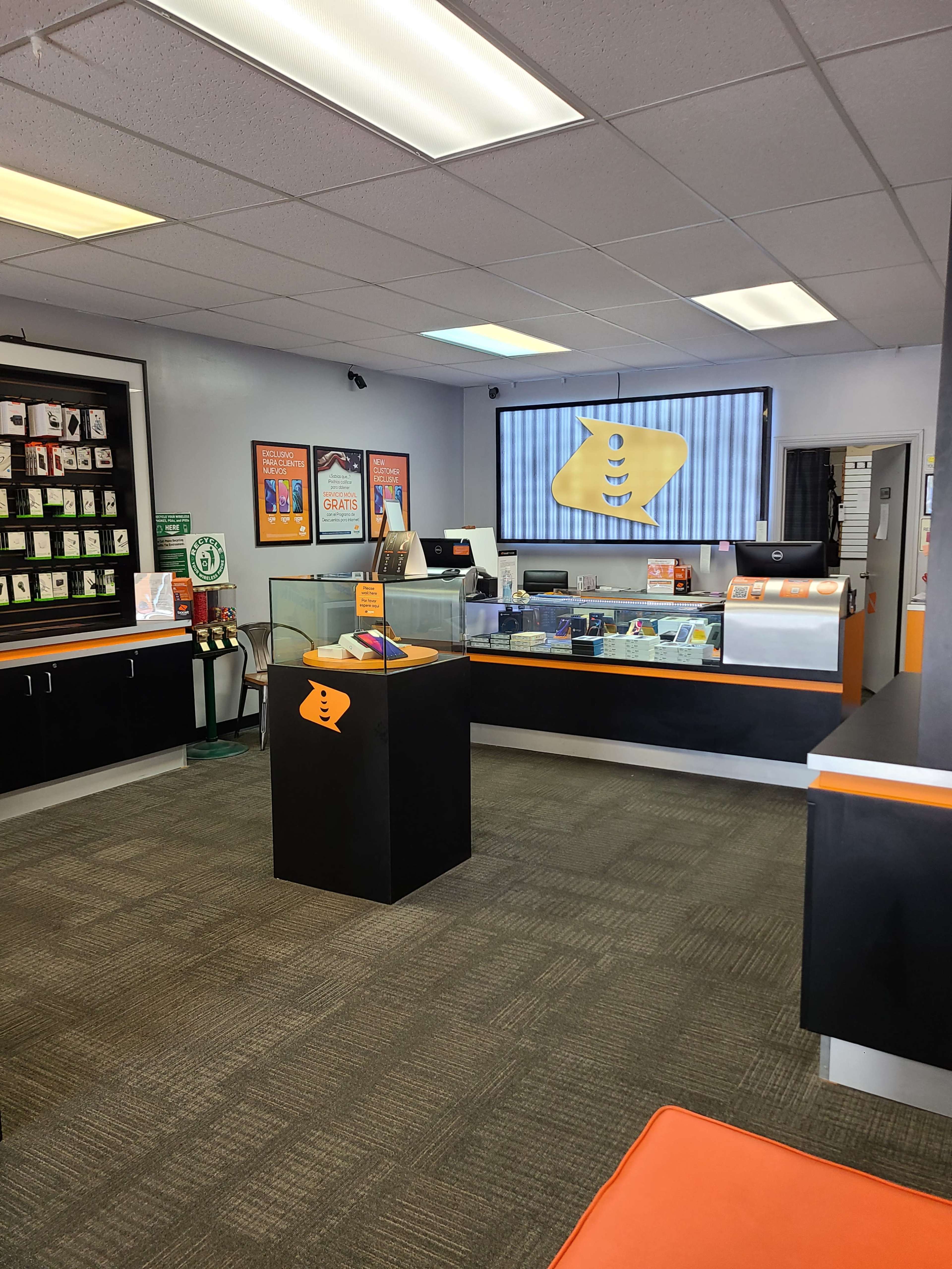 The interior of a retail store featuring a product display area with a counter, a wall of merchandise, and a large screen displaying the store's logo.