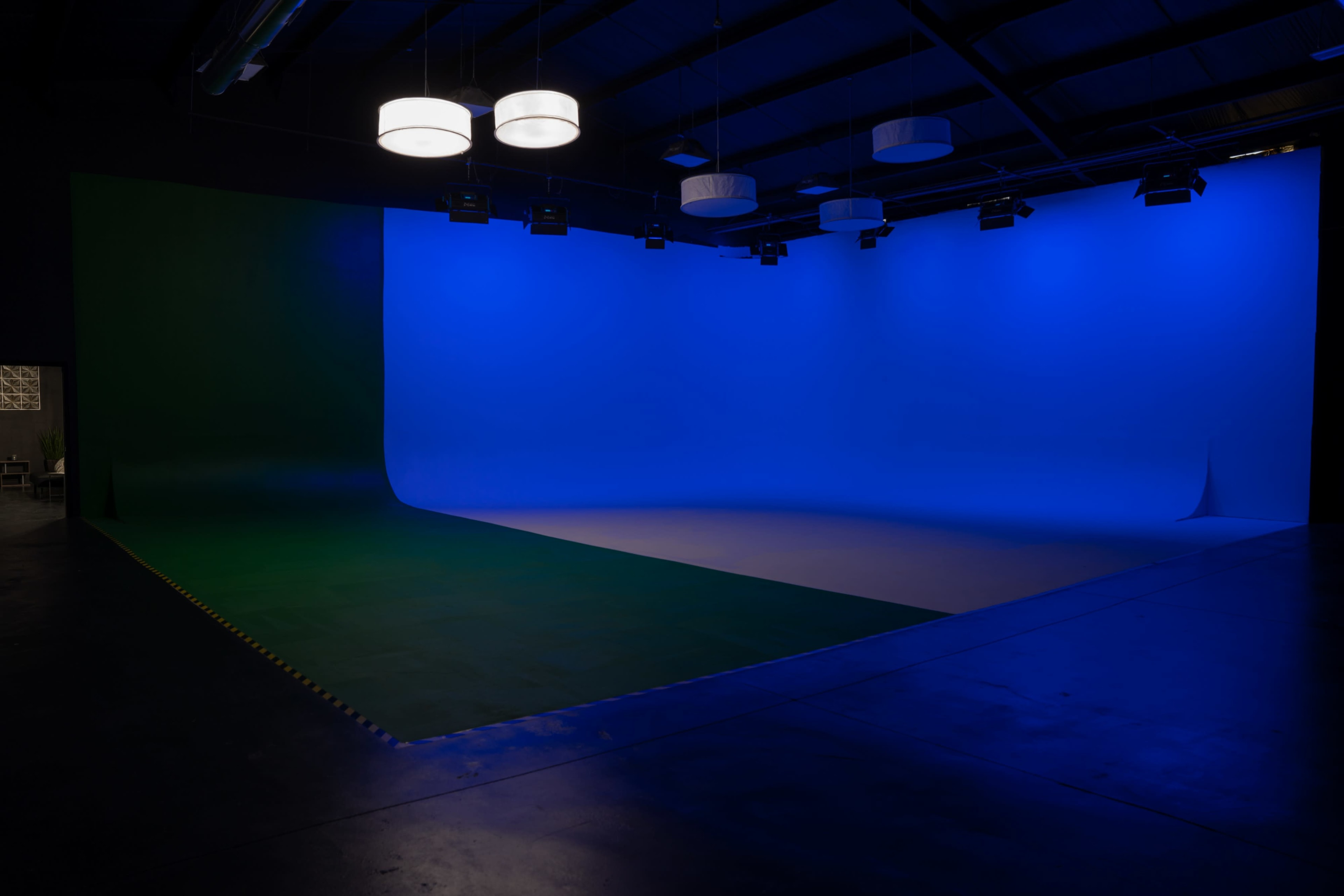 A large studio space with a blue and green backdrop, illuminated by overhead lights.