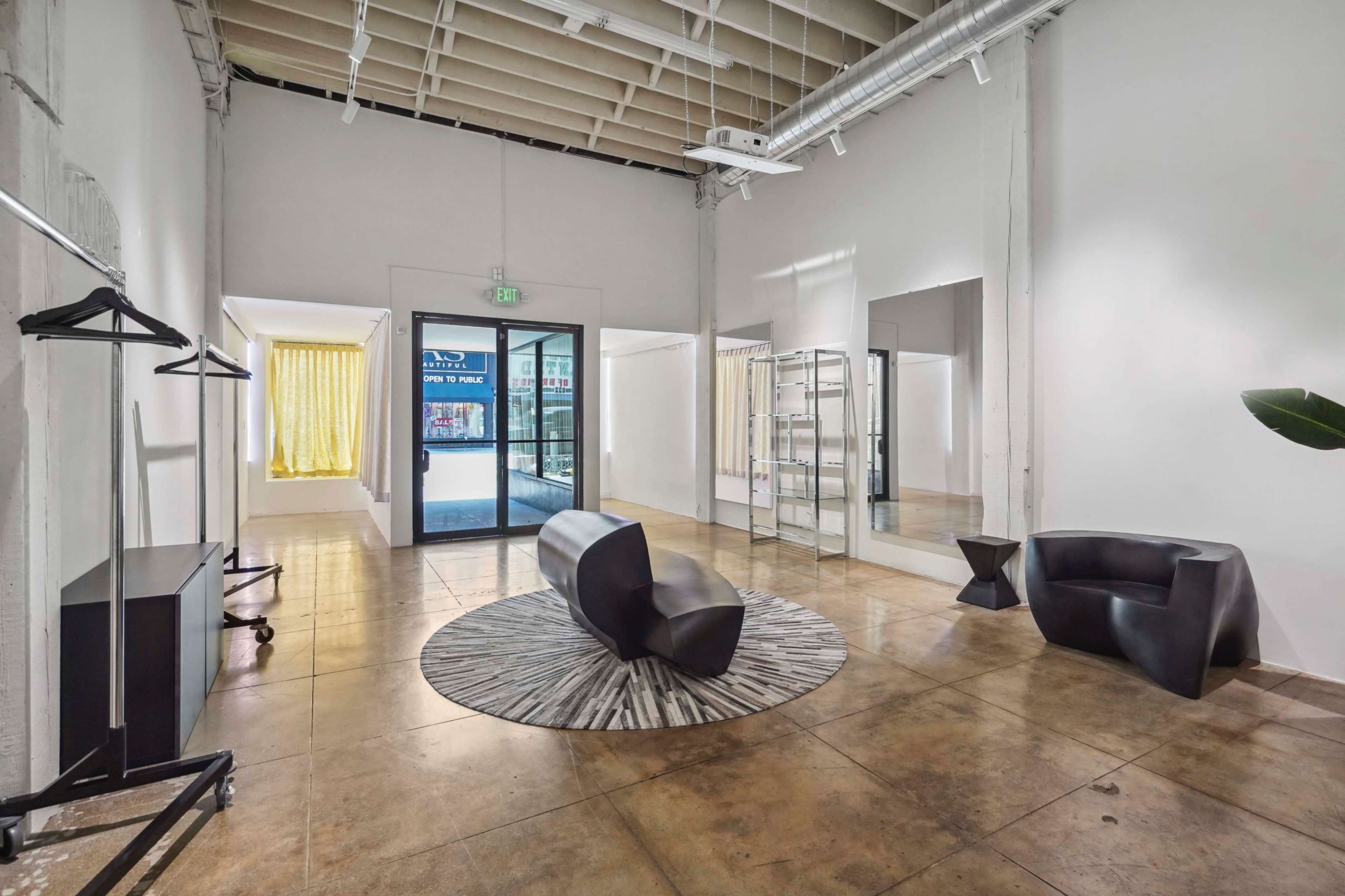 A spacious, modern interior with polished concrete floors, minimal furniture, and large windows allowing natural light to enter.