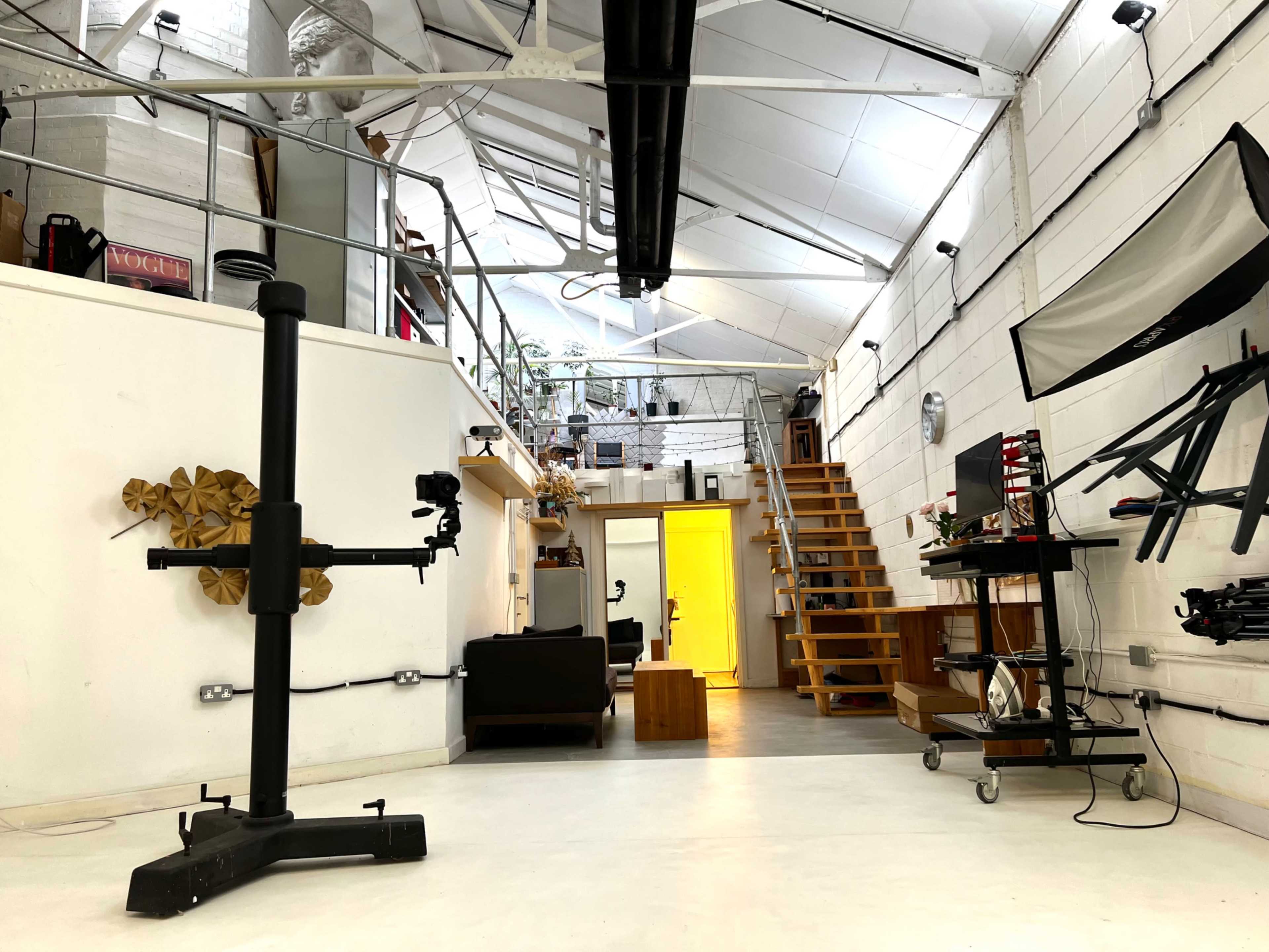 An industrial-style interior space featuring a staircase, furniture, and various equipment, with bright lighting highlighting the area.