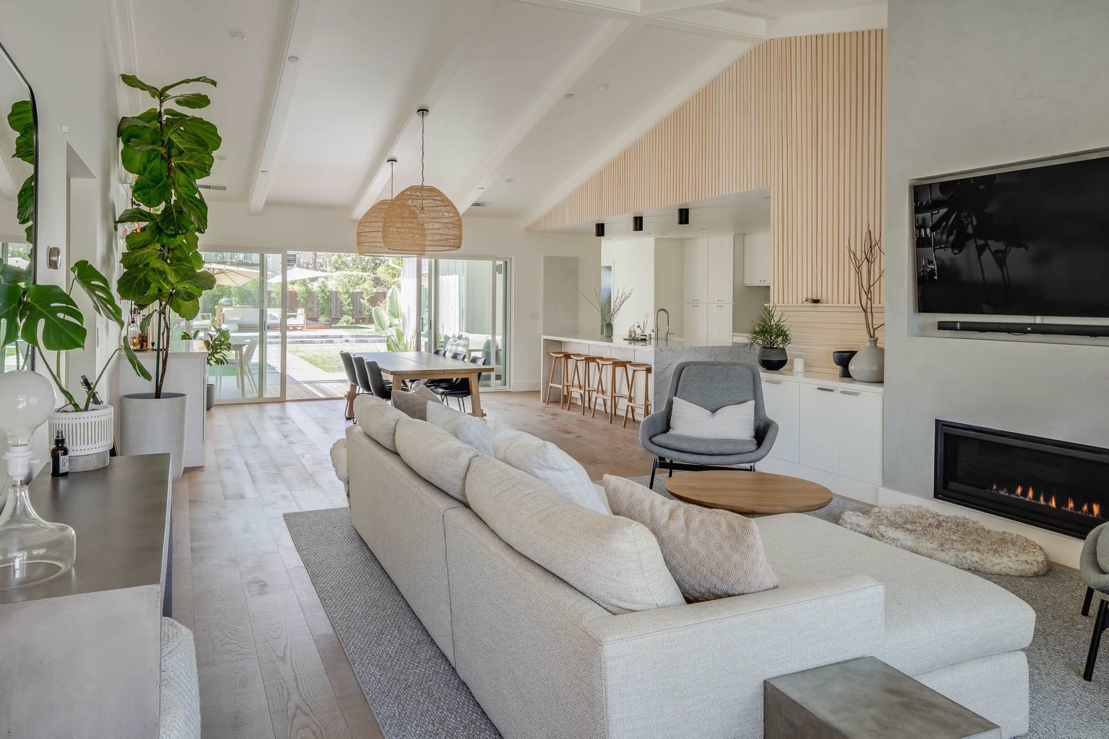A modern living room featuring a light-colored sectional sofa, a wooden coffee table, and large windows overlooking a patio area.