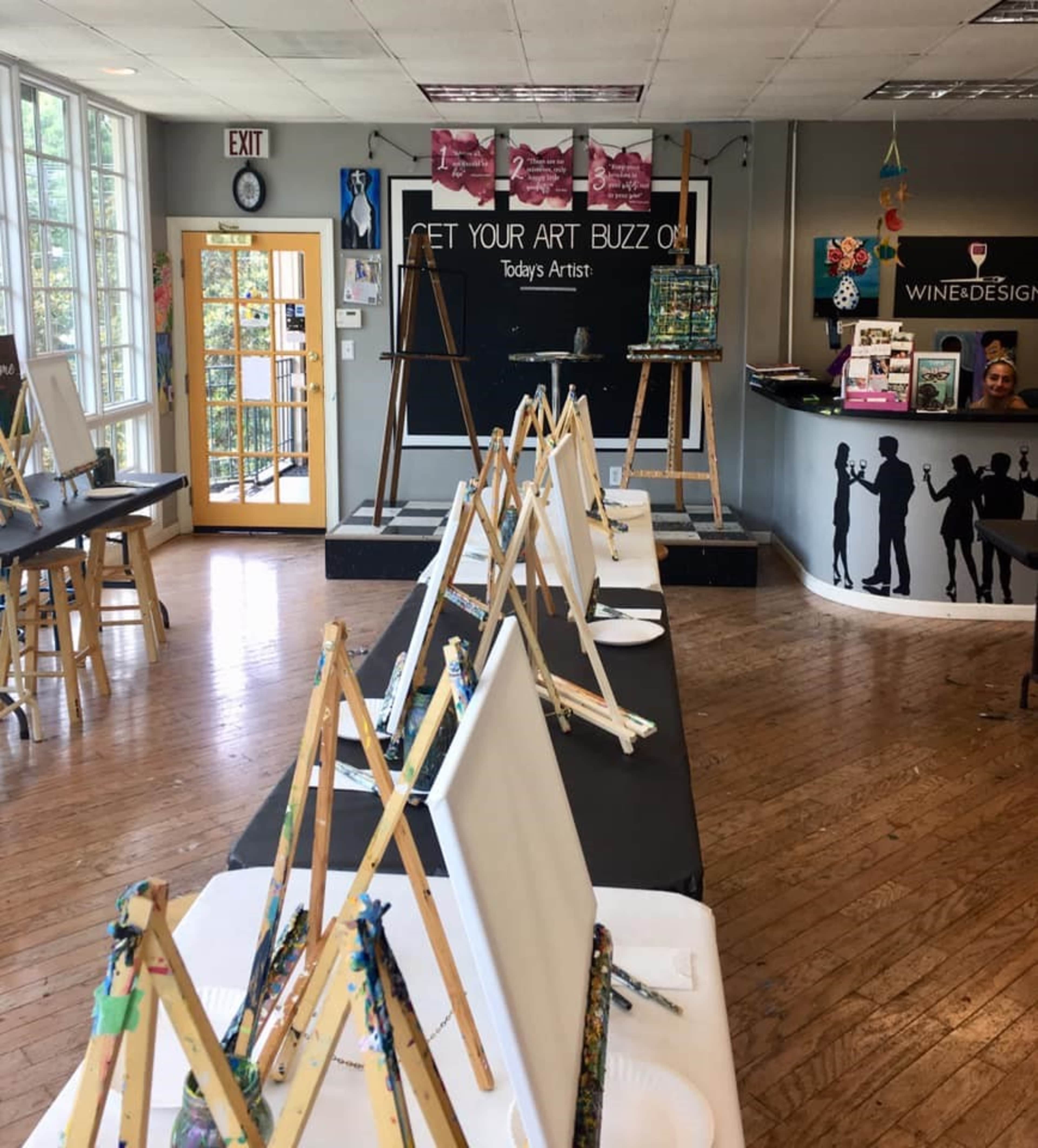 An art studio with multiple easels set up along tables, ready for a painting class.