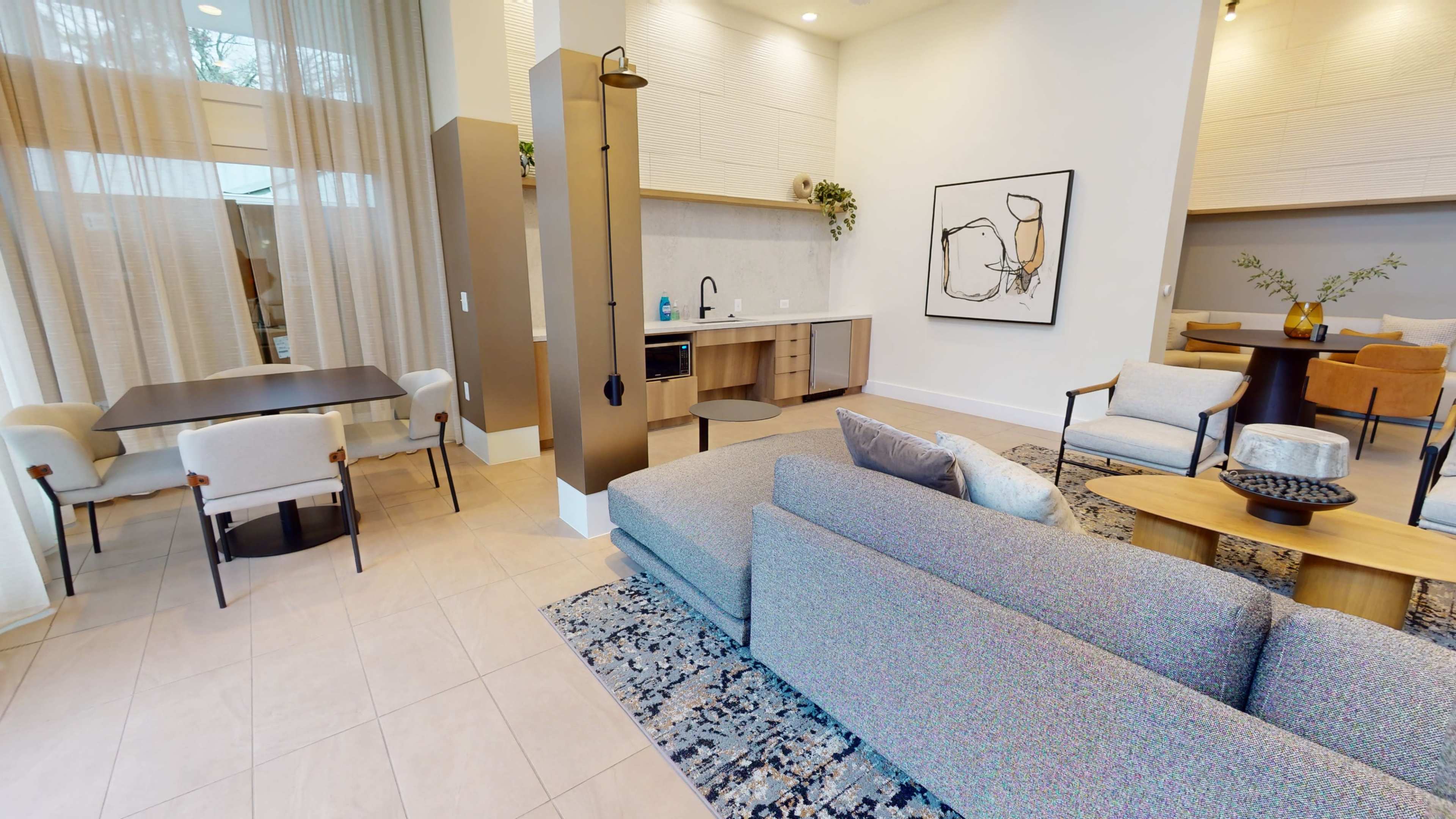A modern living space with a kitchen area, dining table, and a comfortable seating arrangement featuring a sofa and chairs.