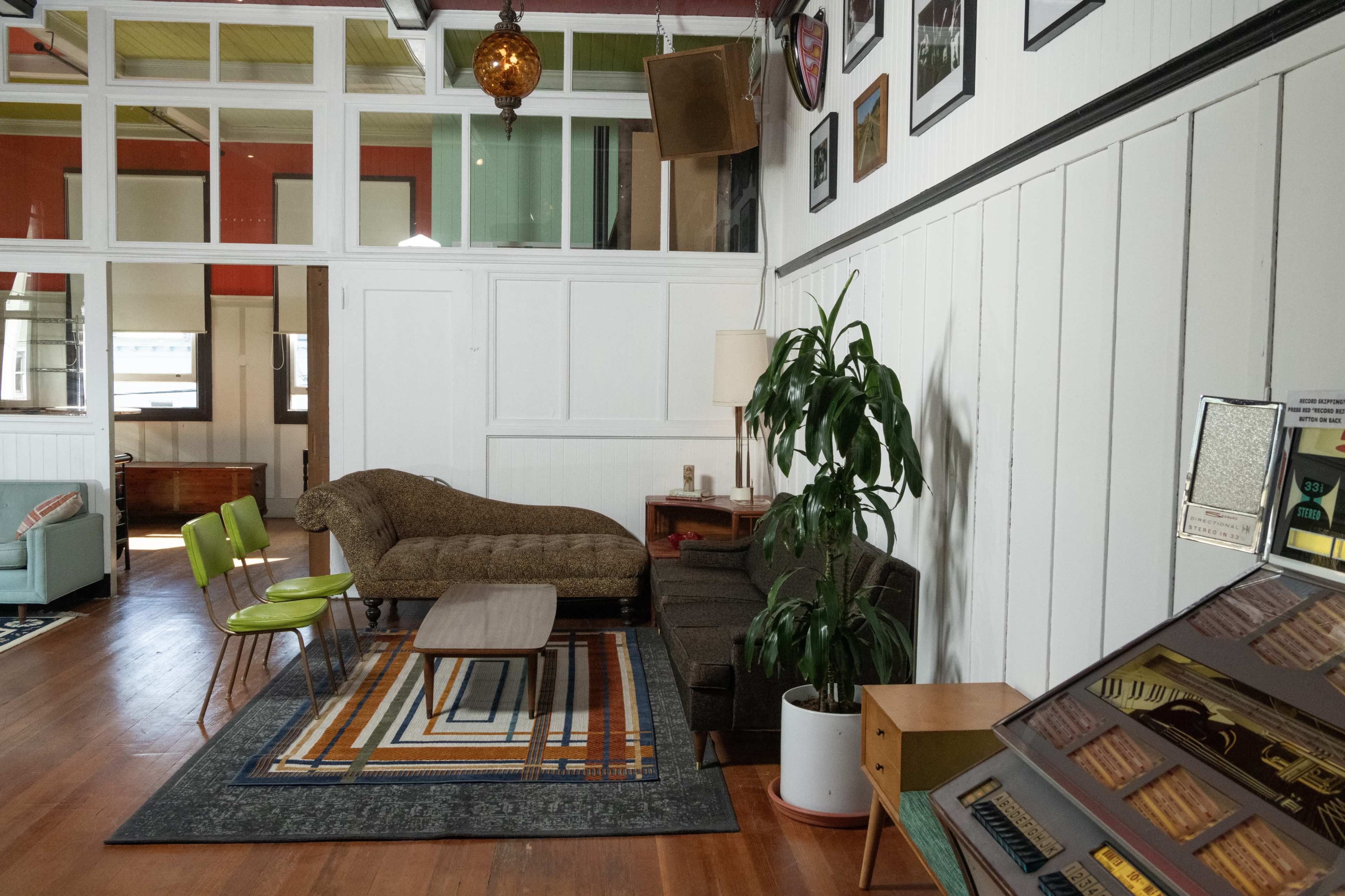 A cozy interior space with a couch, two green chairs, a coffee table, and decorative wall art.