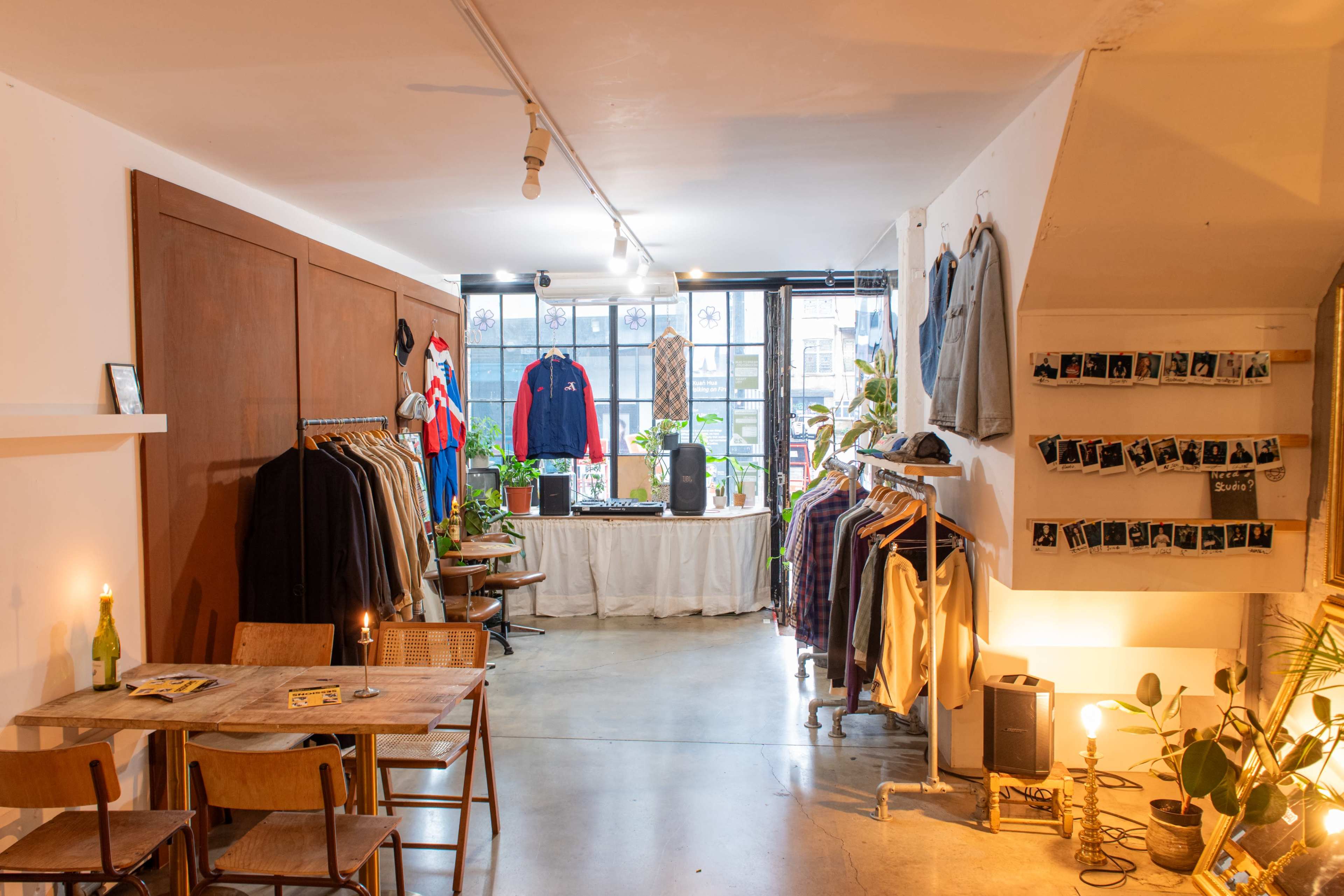 The image shows a trendy clothing store interior with racks of apparel, a table, and plant decorations.