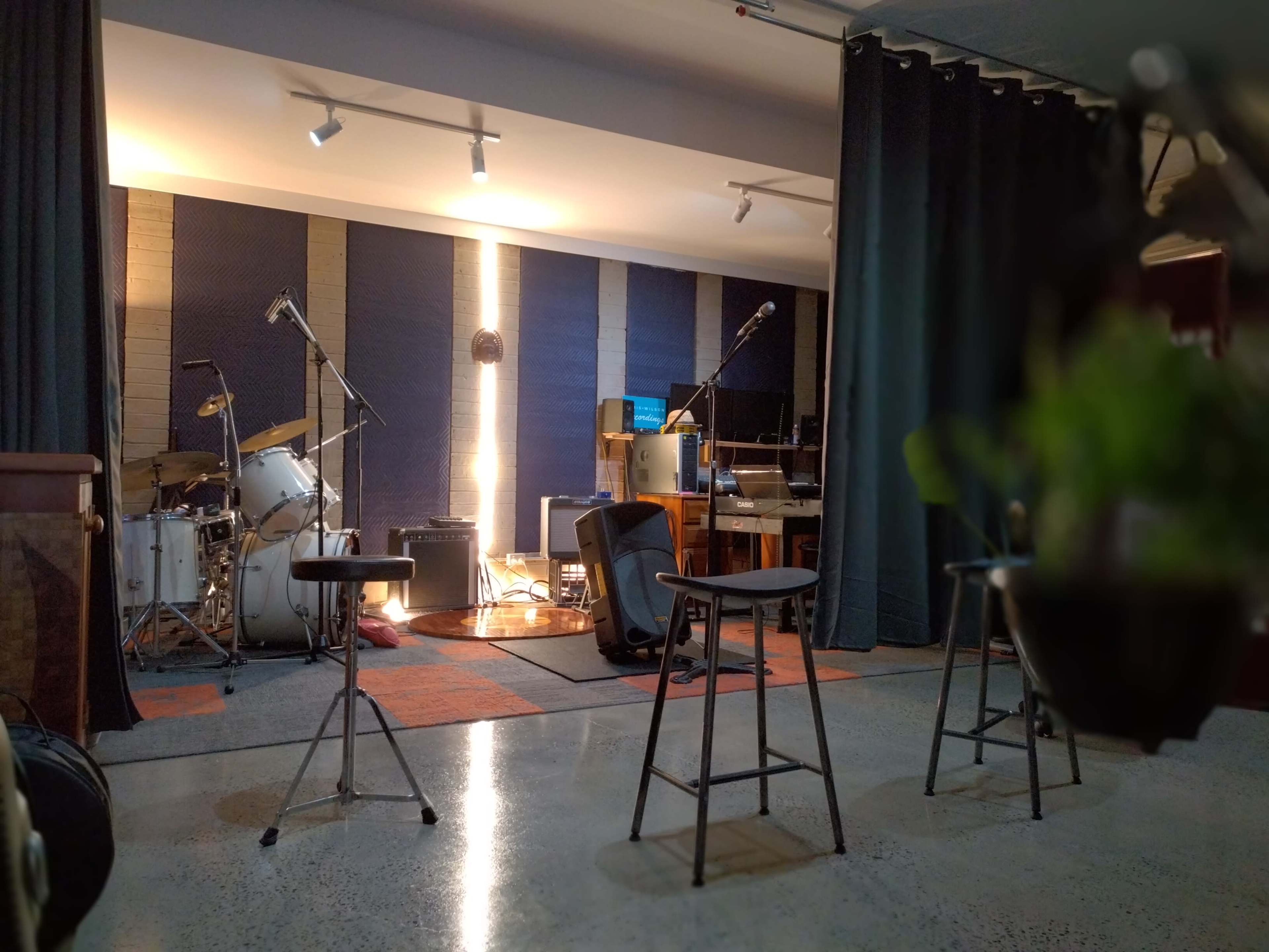 A music studio with a drum set, microphones, and various instruments arranged in a well-lit space.