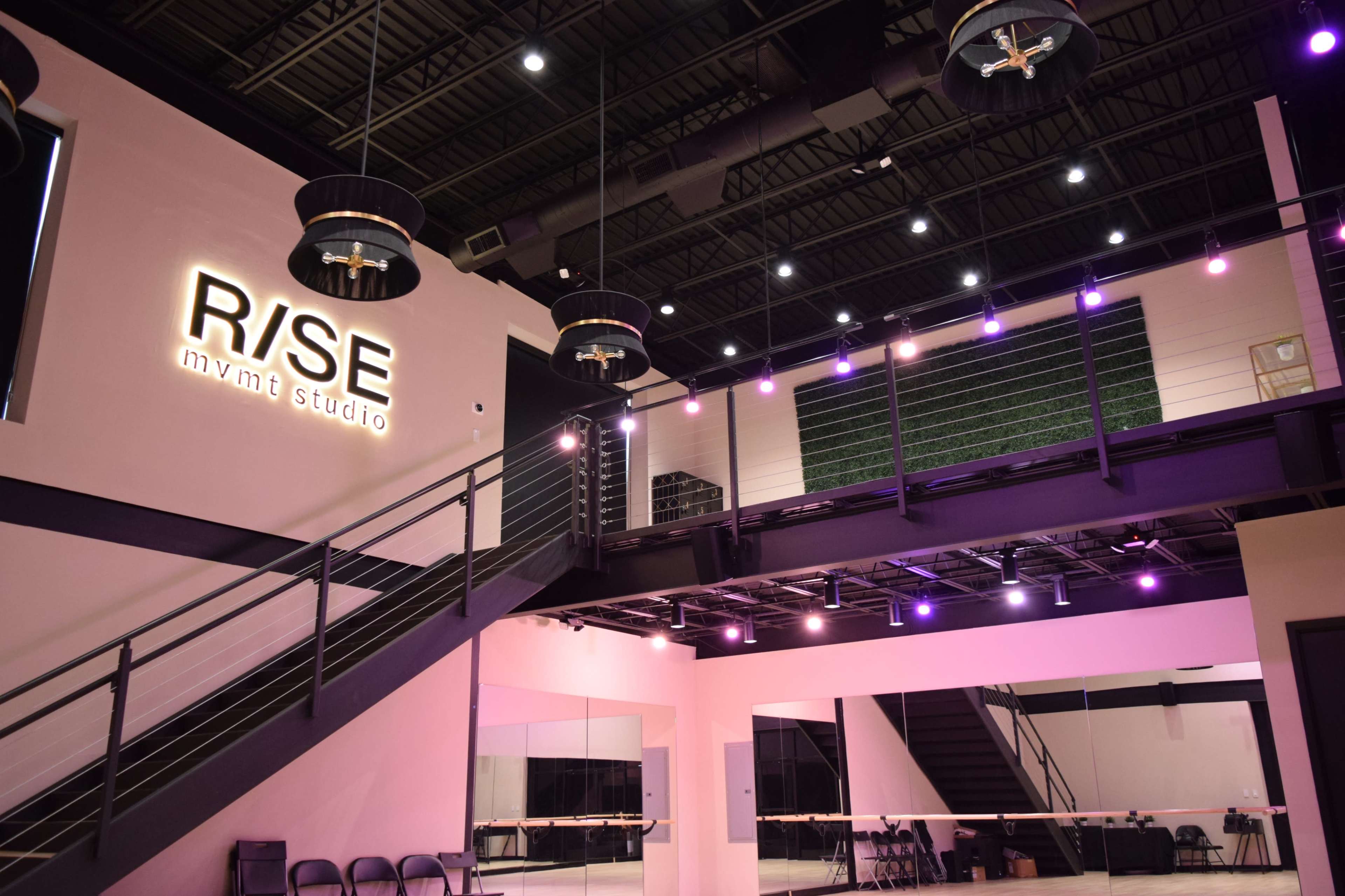 A modern studio space with a two-level layout, featuring a large sign that reads "R/SE mving studio" and various lighting fixtures.