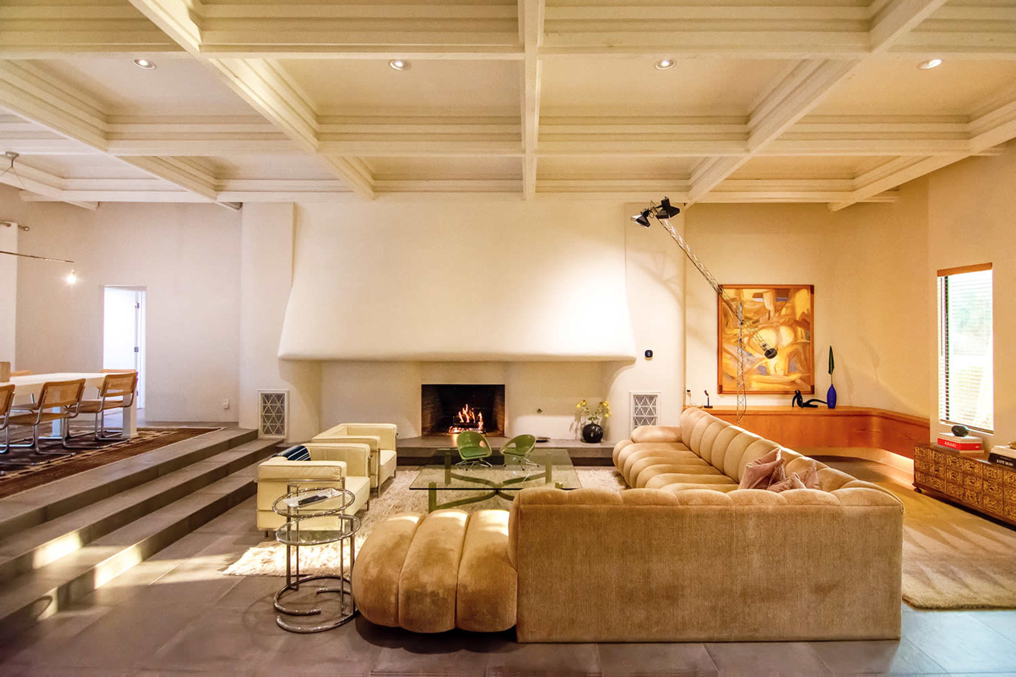 A spacious living room with a large sectional sofa, a fireplace, and a dining area in the background.