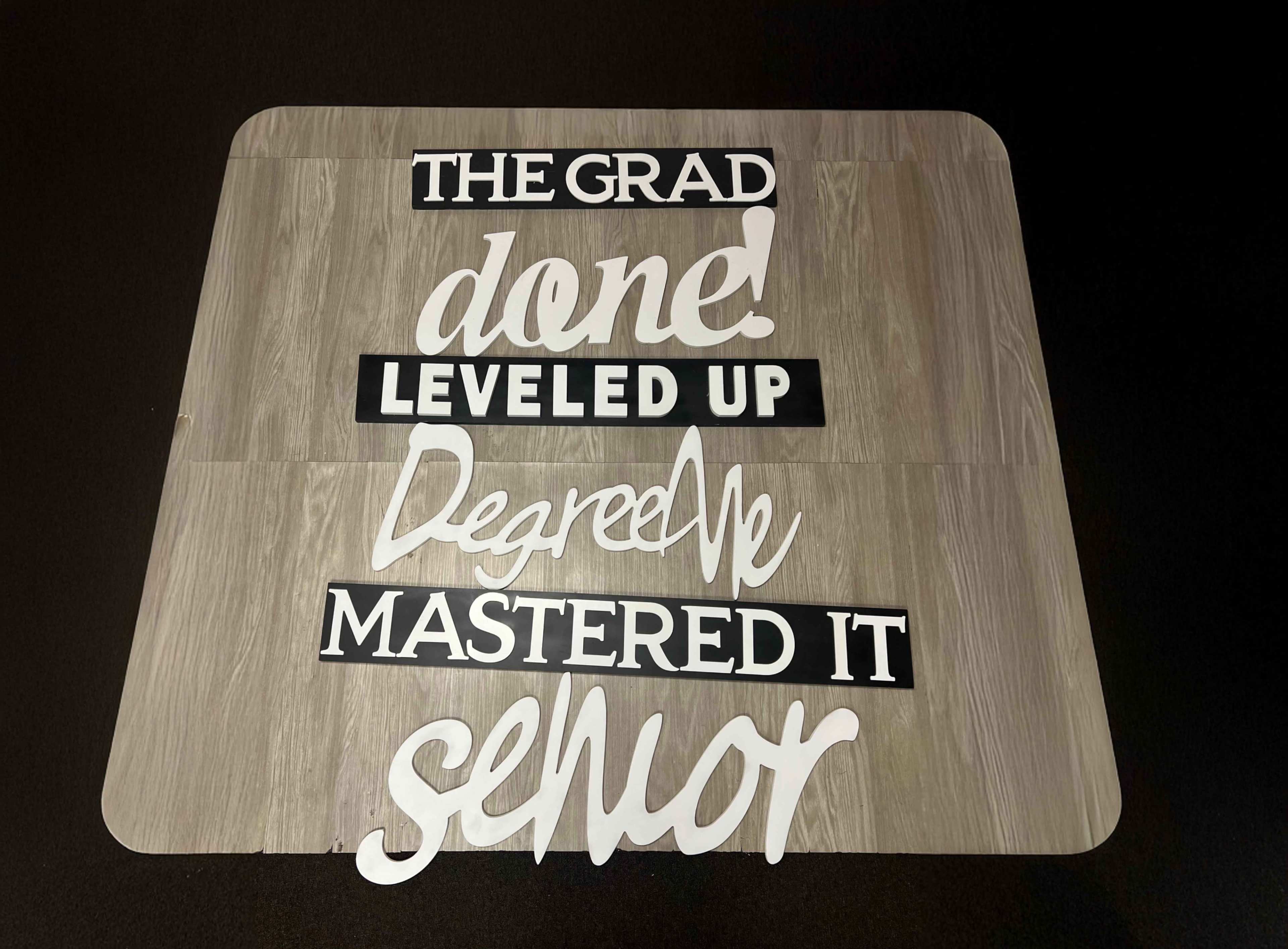 A flat surface displays various paper cutouts with phrases celebrating graduation and achievement.