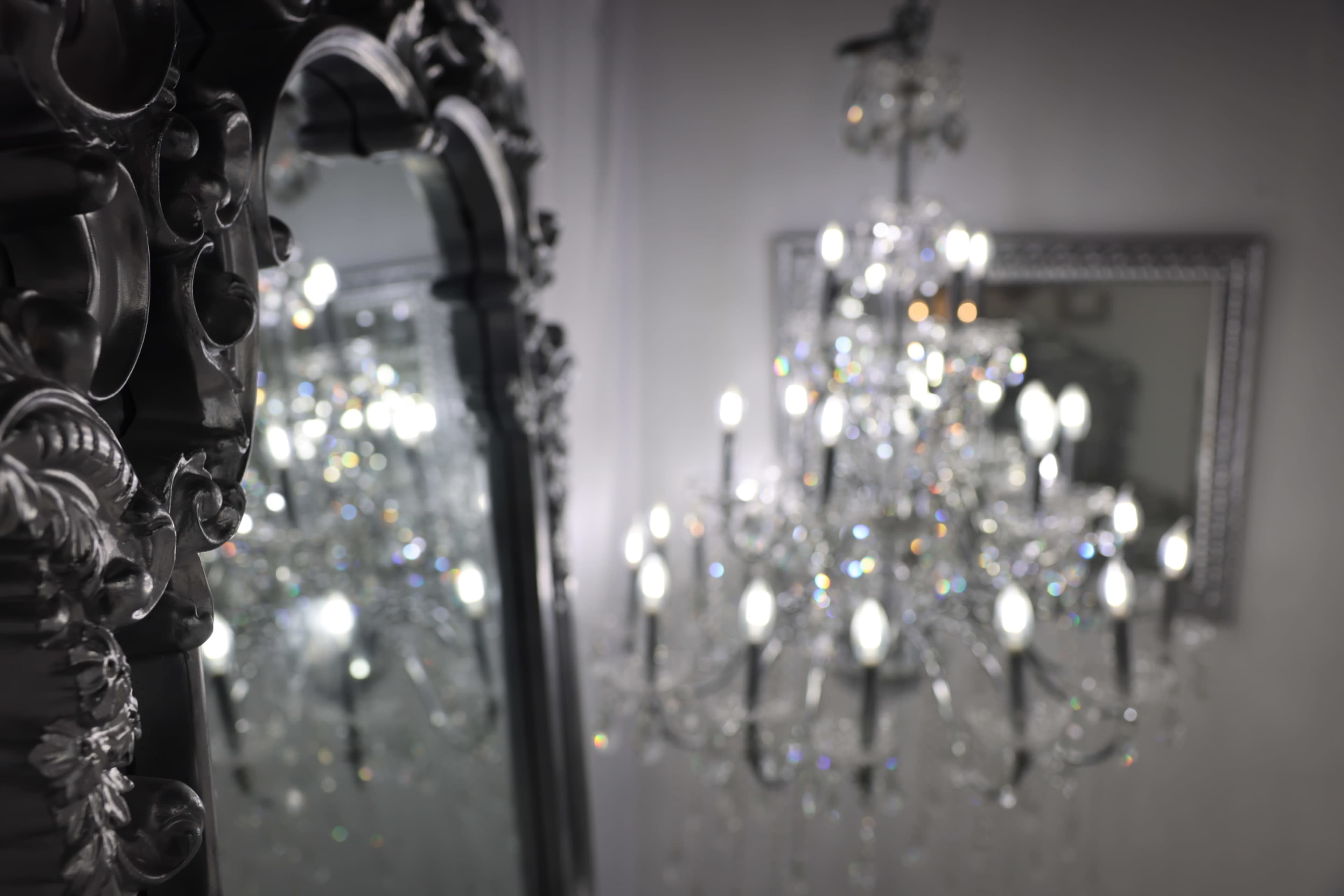 The image shows an ornate mirror reflecting a crystal chandelier with illuminated bulbs.