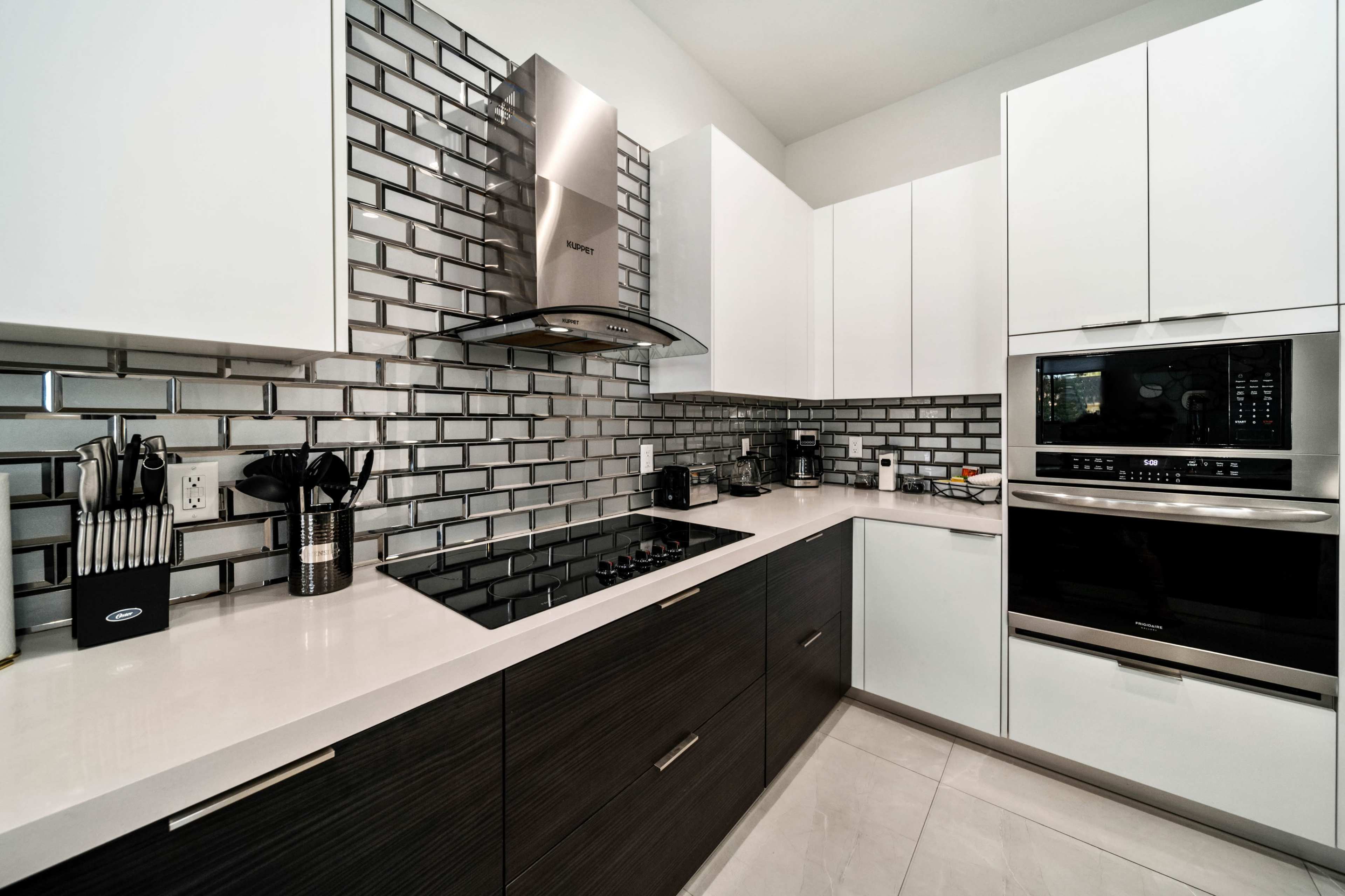 A modern kitchen features a gray tiled backsplash, stainless steel appliances, and sleek cabinetry.