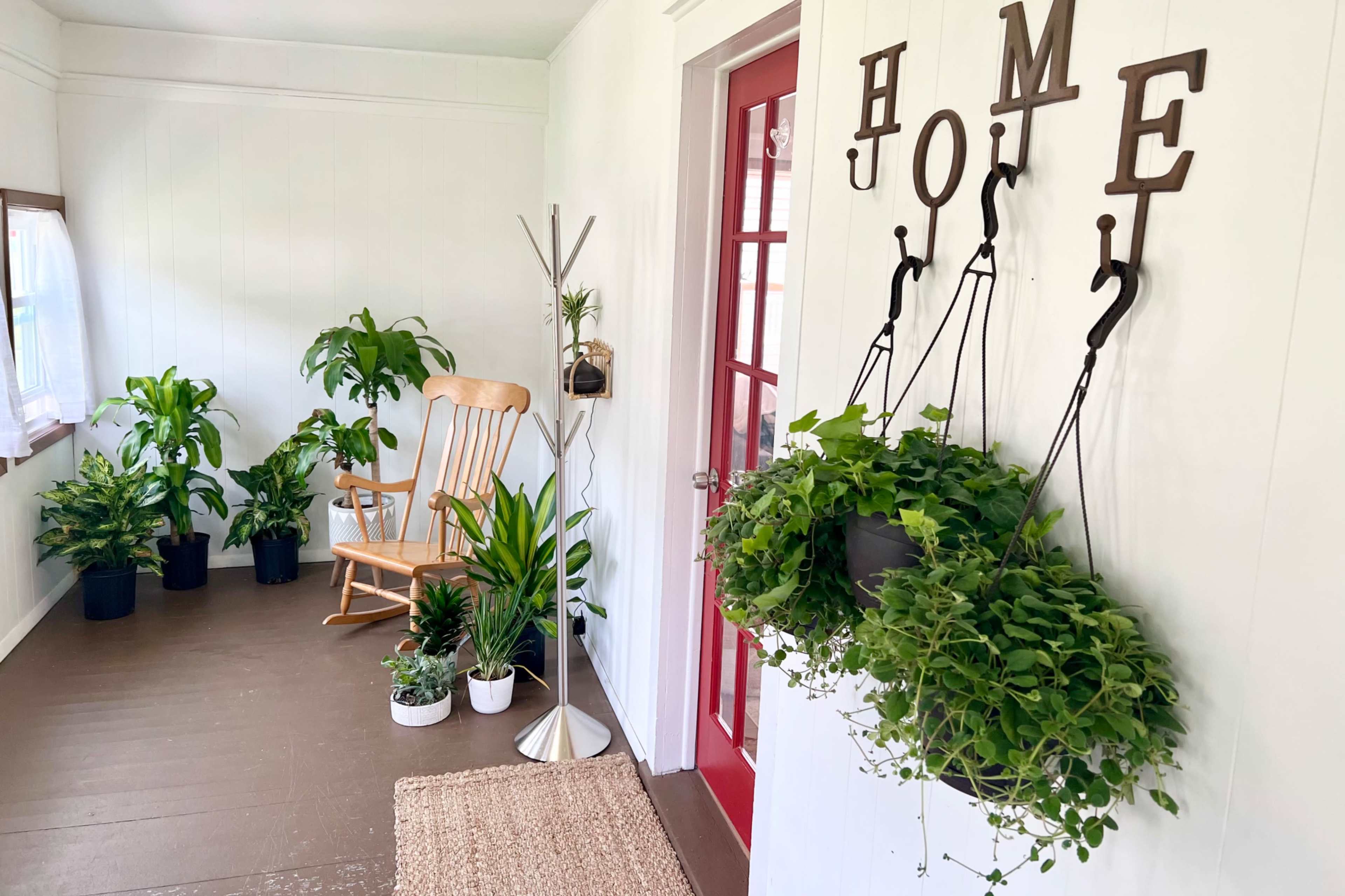 A bright entryway featuring a rocking chair, several potted plants, and a decorative sign spelling "HOME" on the wall.