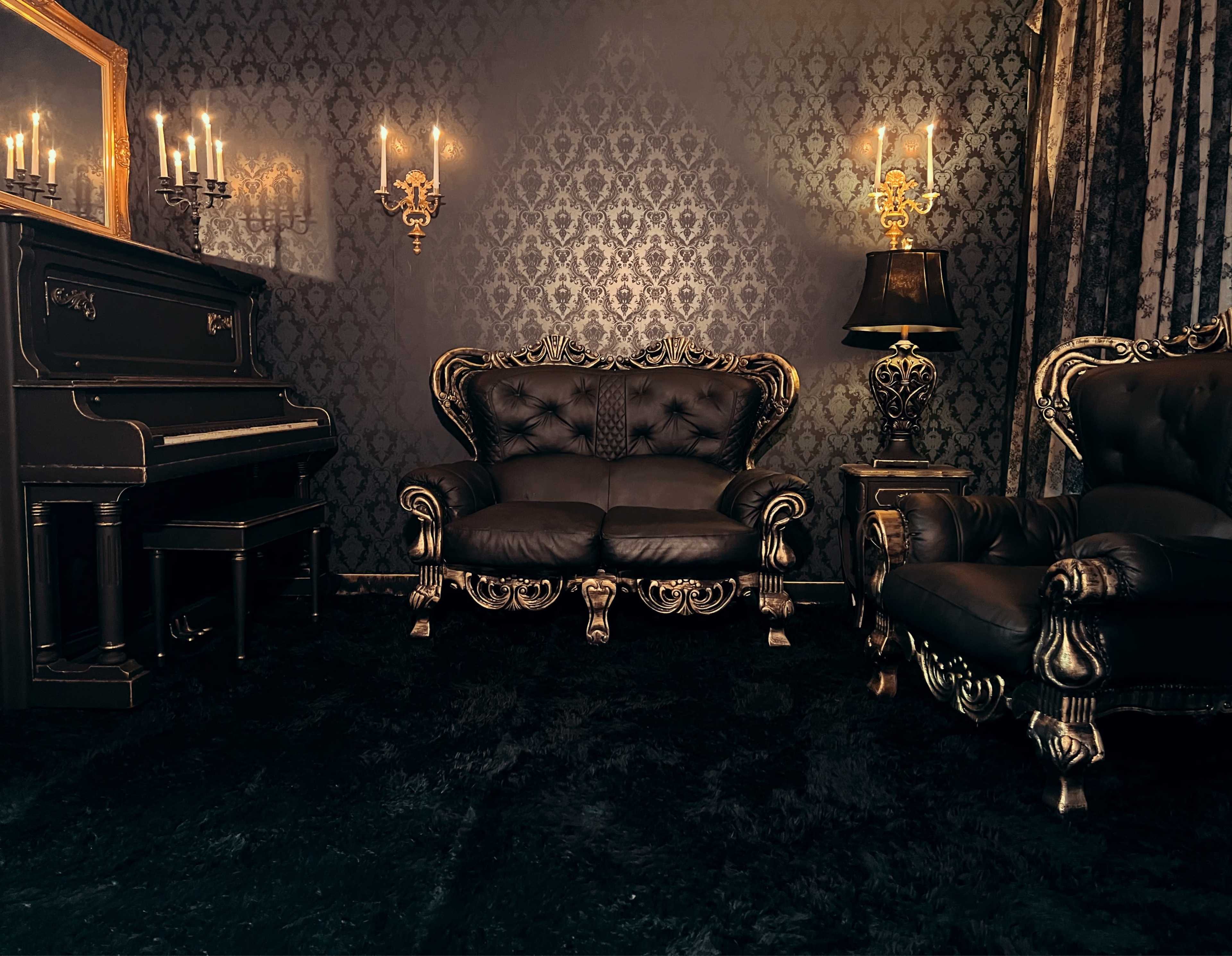 The image shows a darkly themed room with ornate furniture, including a black piano and a seating arrangement featuring a sofa and armchair, all adorned with golden accents against patterned wallpaper.