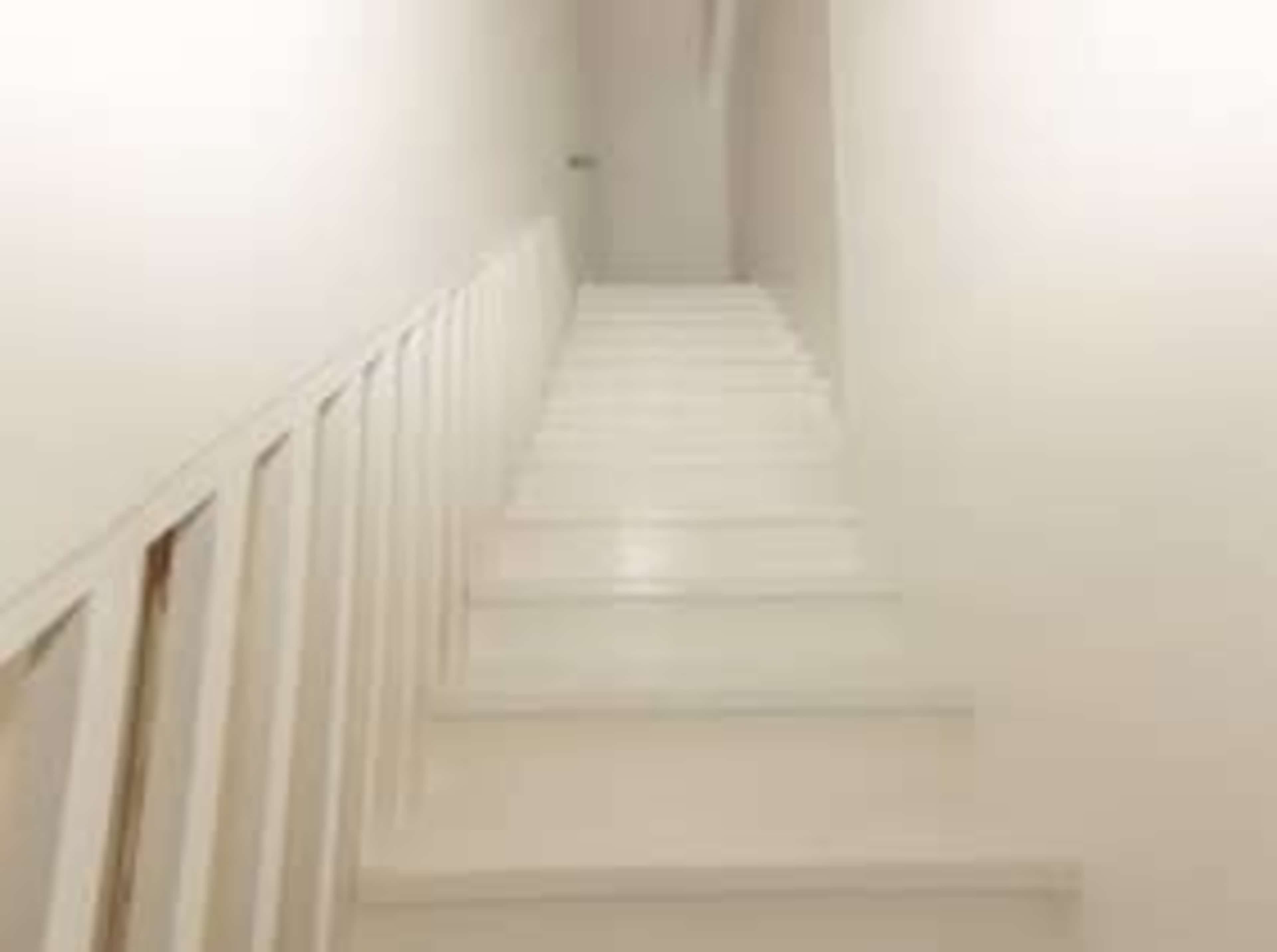A white staircase leads upward to a dimly lit corridor.