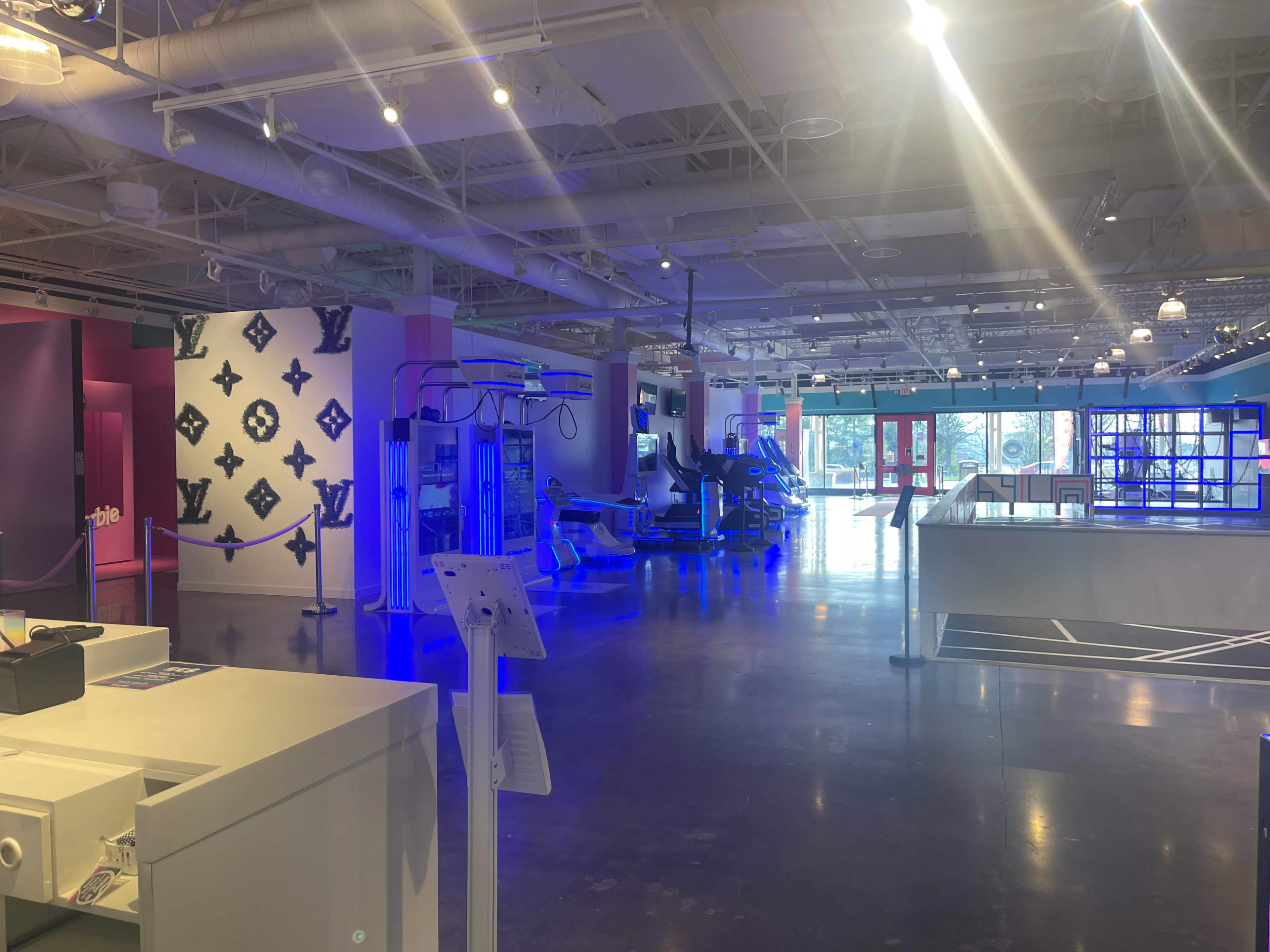 A spacious, brightly lit interior of a modern retail space with workout equipment and colorful wall designs.