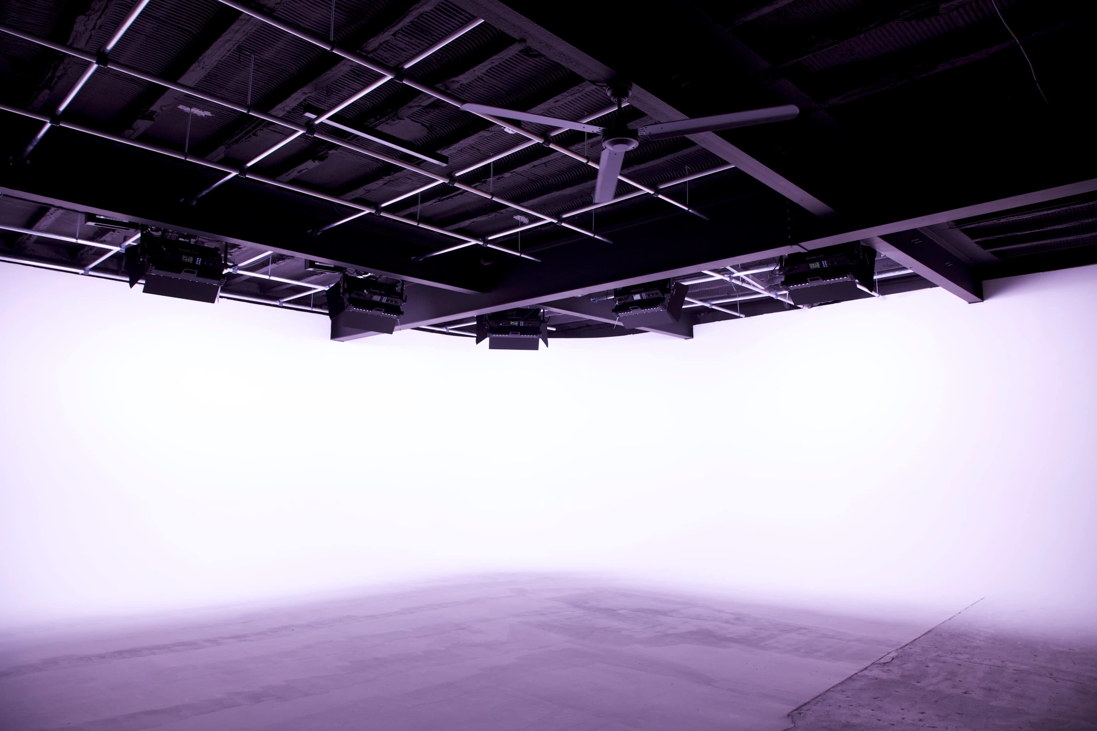 A blank studio space with a smooth floor and minimal lighting equipment installed overhead.