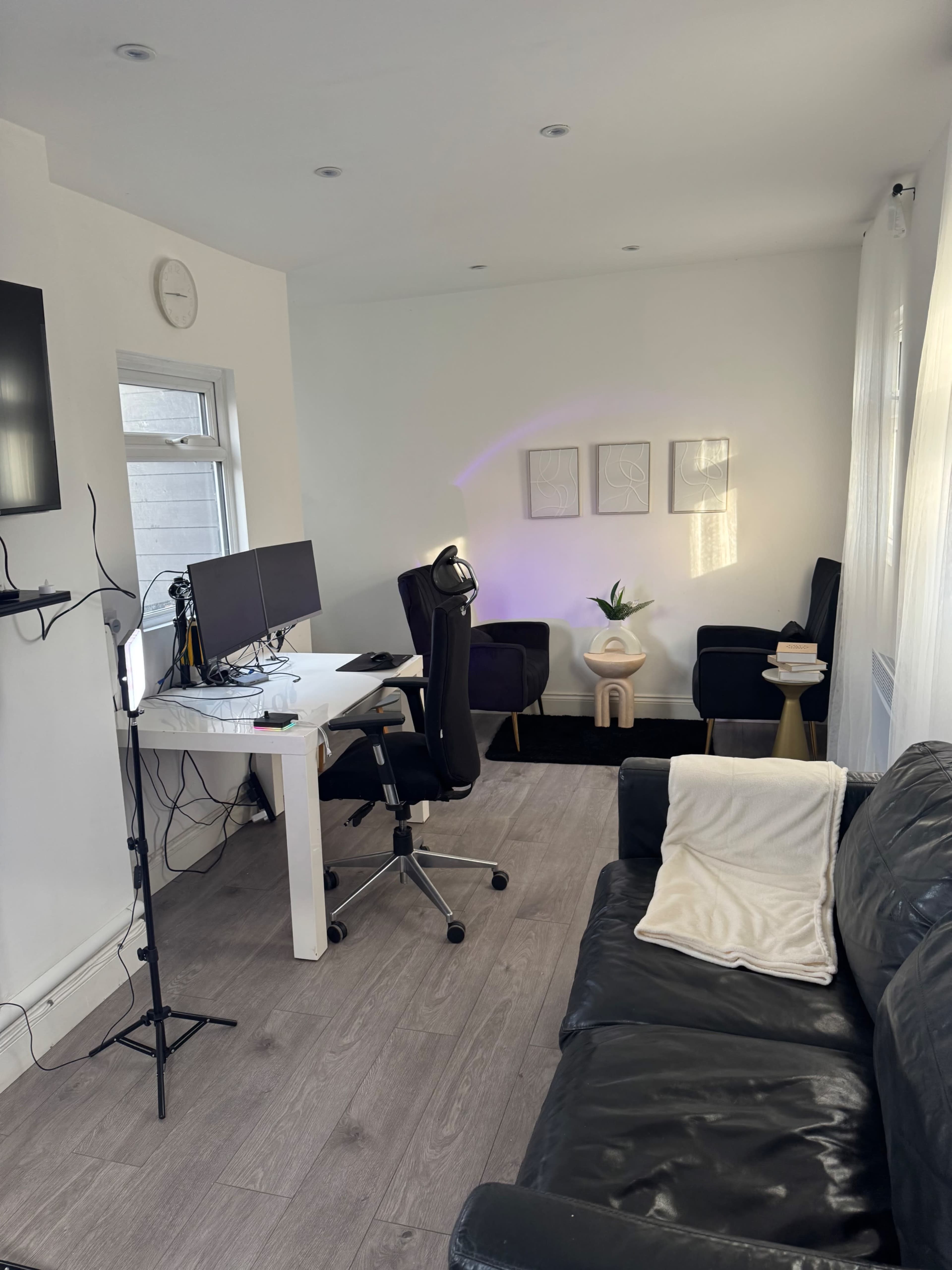 The image shows a modern home office space with a desk, two chairs, a couch, and decorative lighting.
