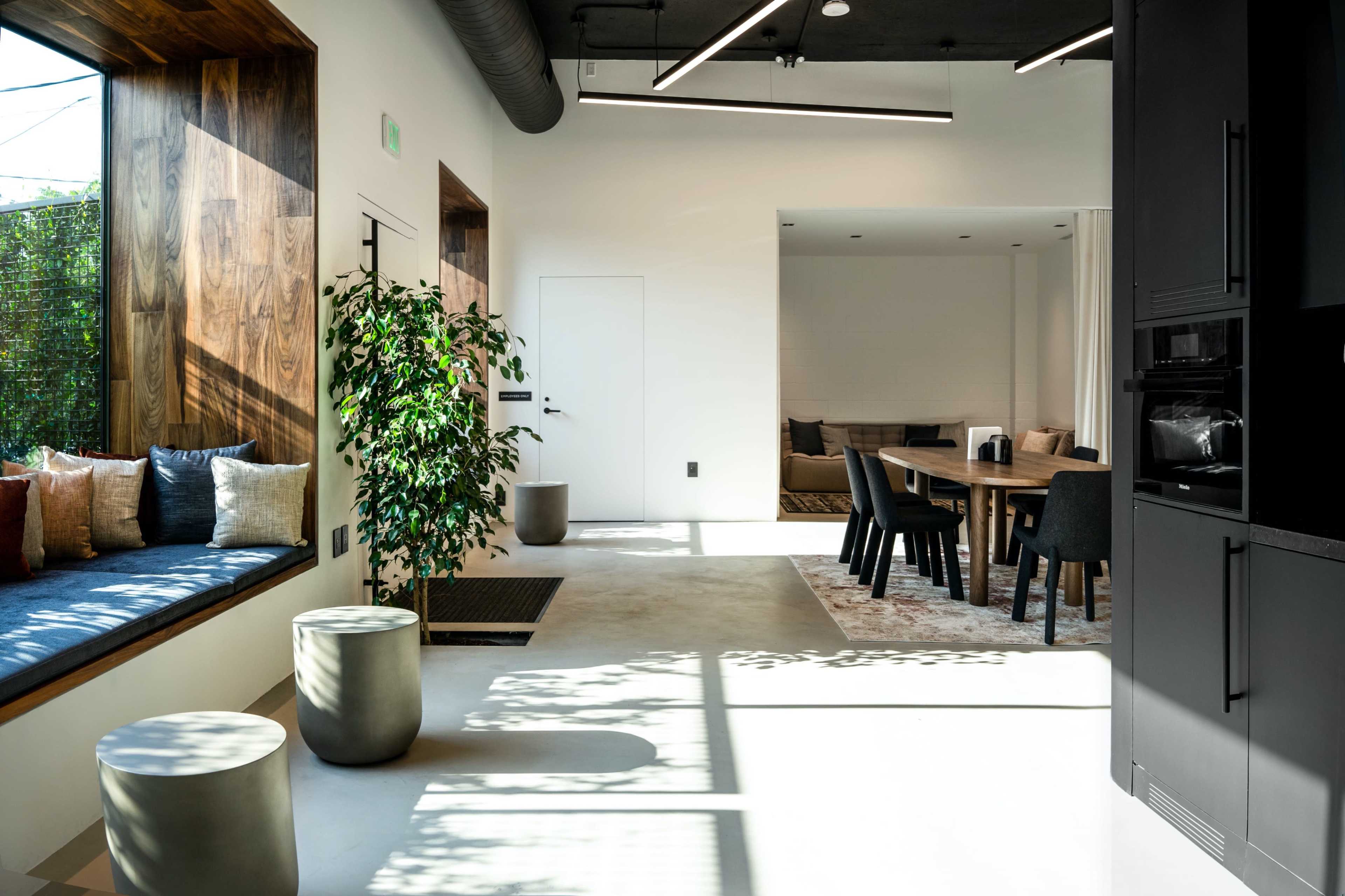 A modern, open-concept living space with a dining area, kitchen, and a cozy seating nook filled with cushions.