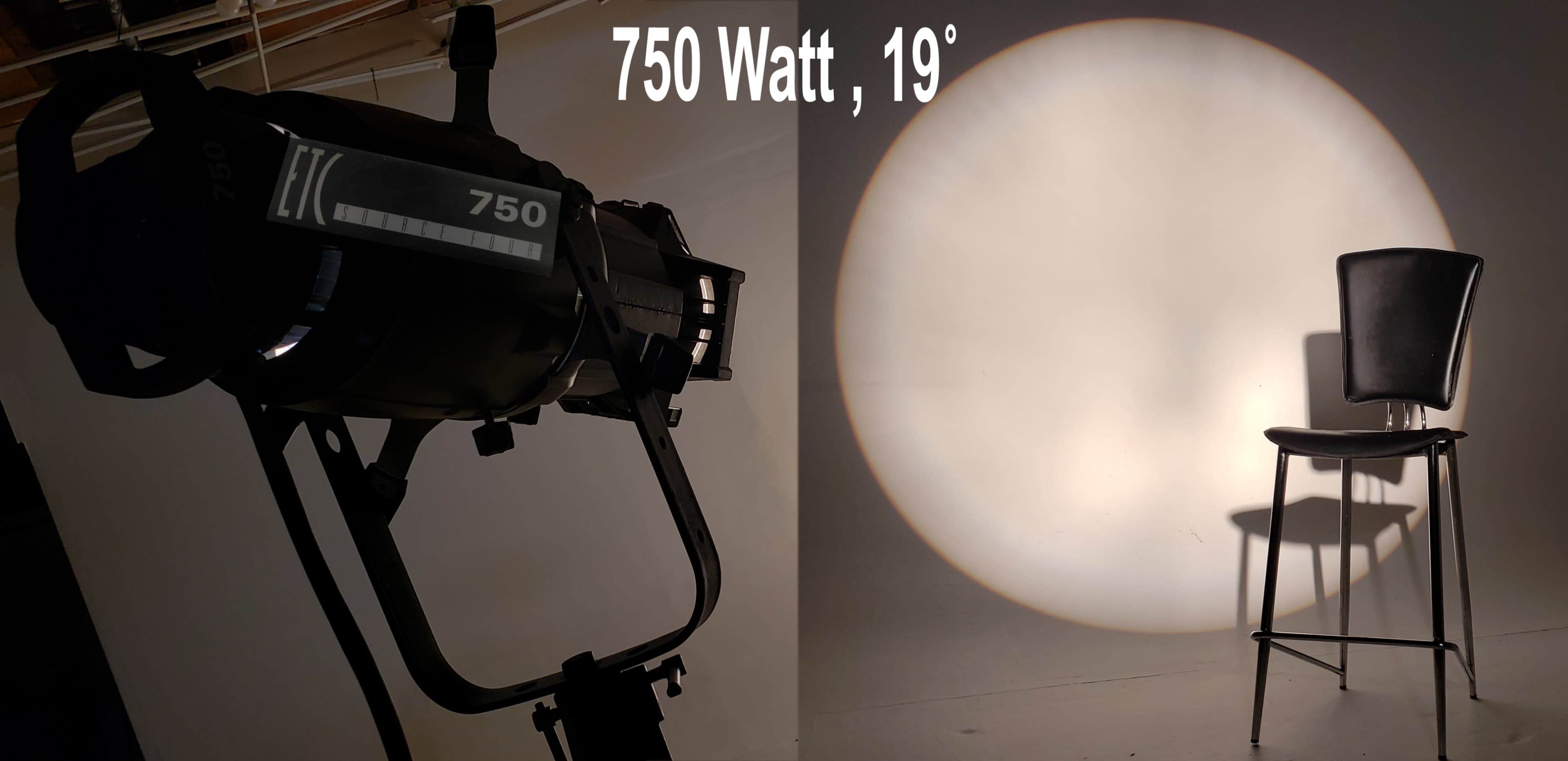 A 750-watt spotlight casts a round shadow on a wall beside an empty black chair.