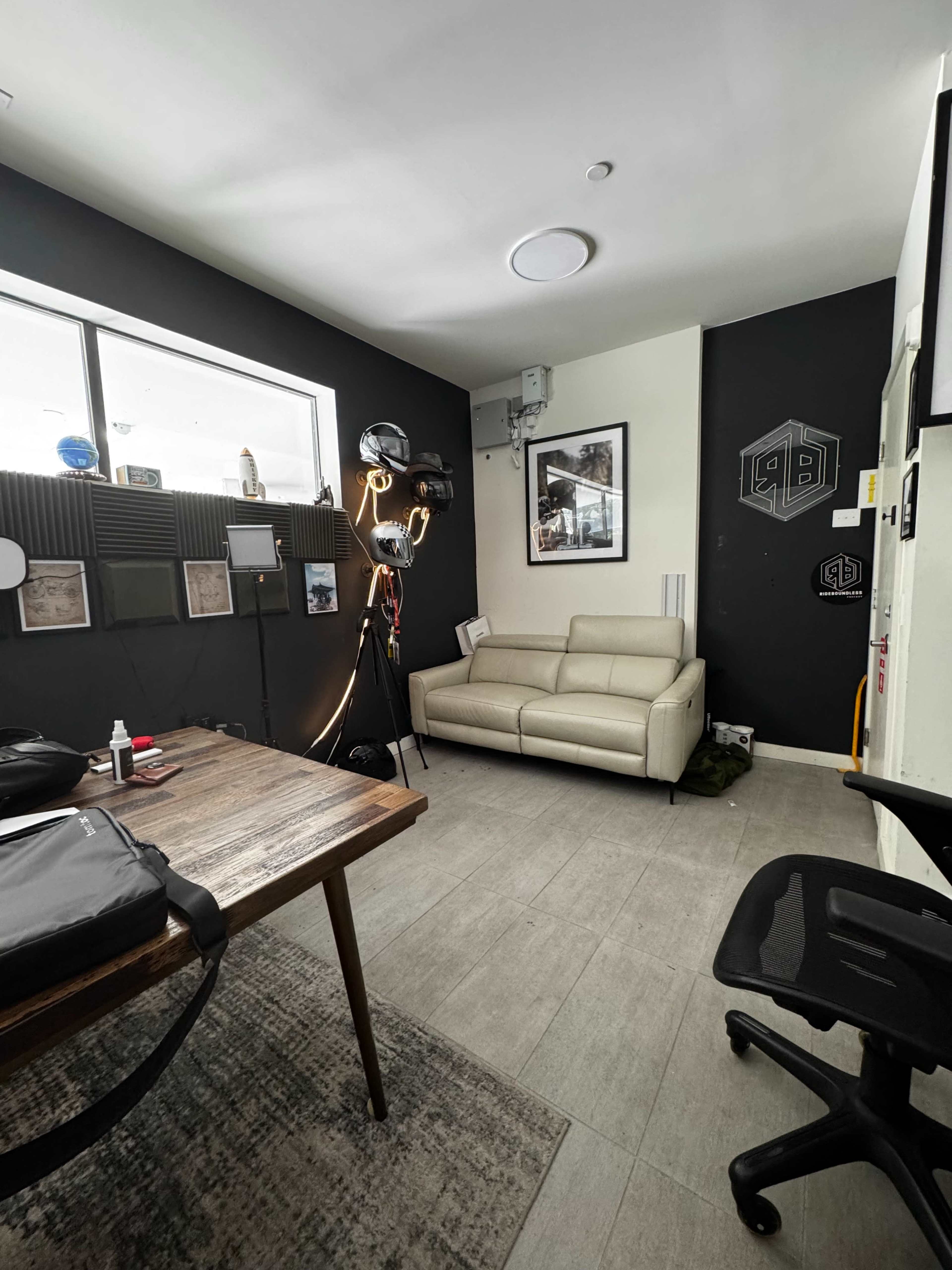 A modern office space featuring a light-colored sofa, a wooden table, and various wall decorations including a logo and photographs.