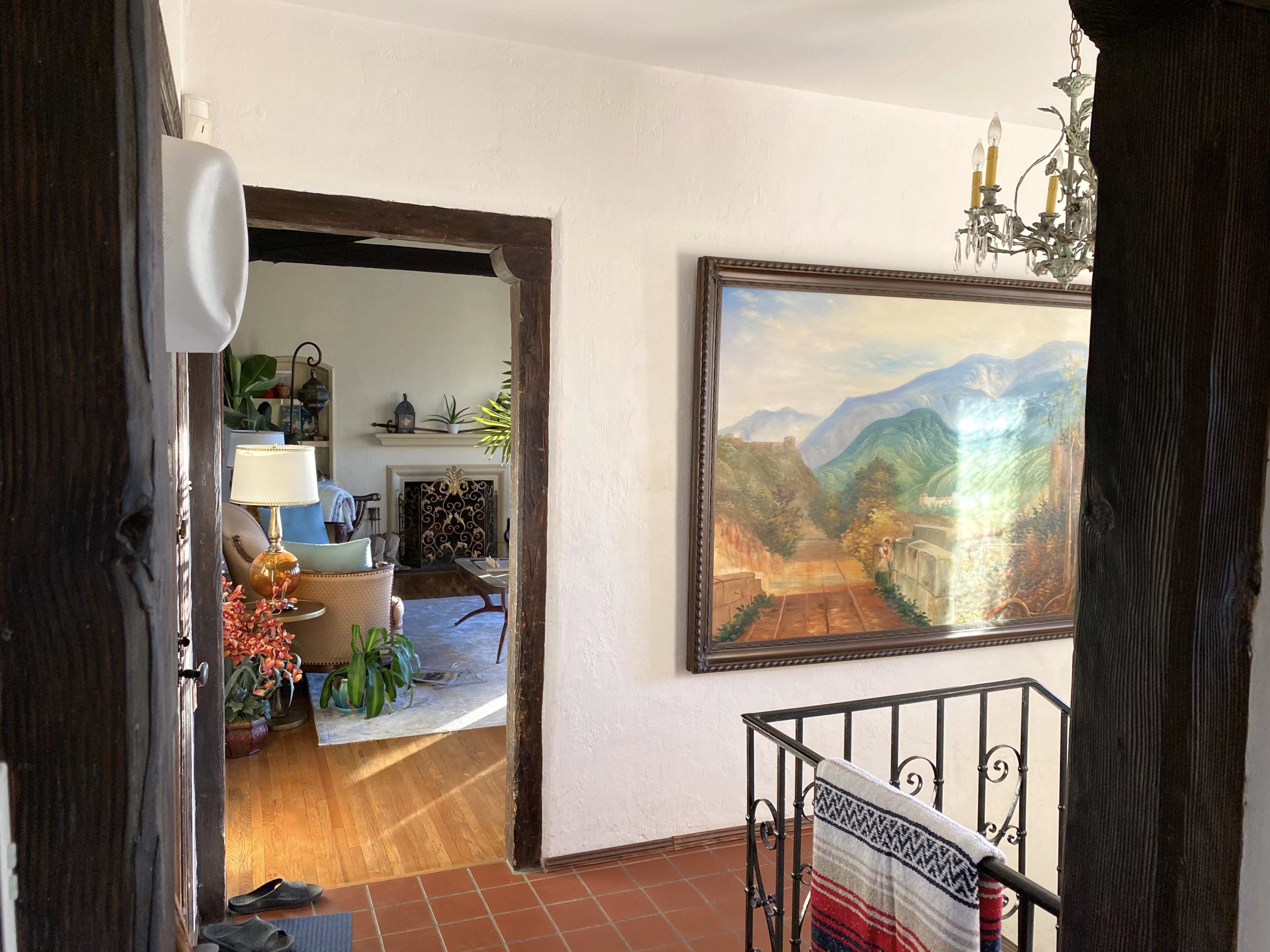 A hallway leads to a cozy living room featuring a large landscape painting on the wall.