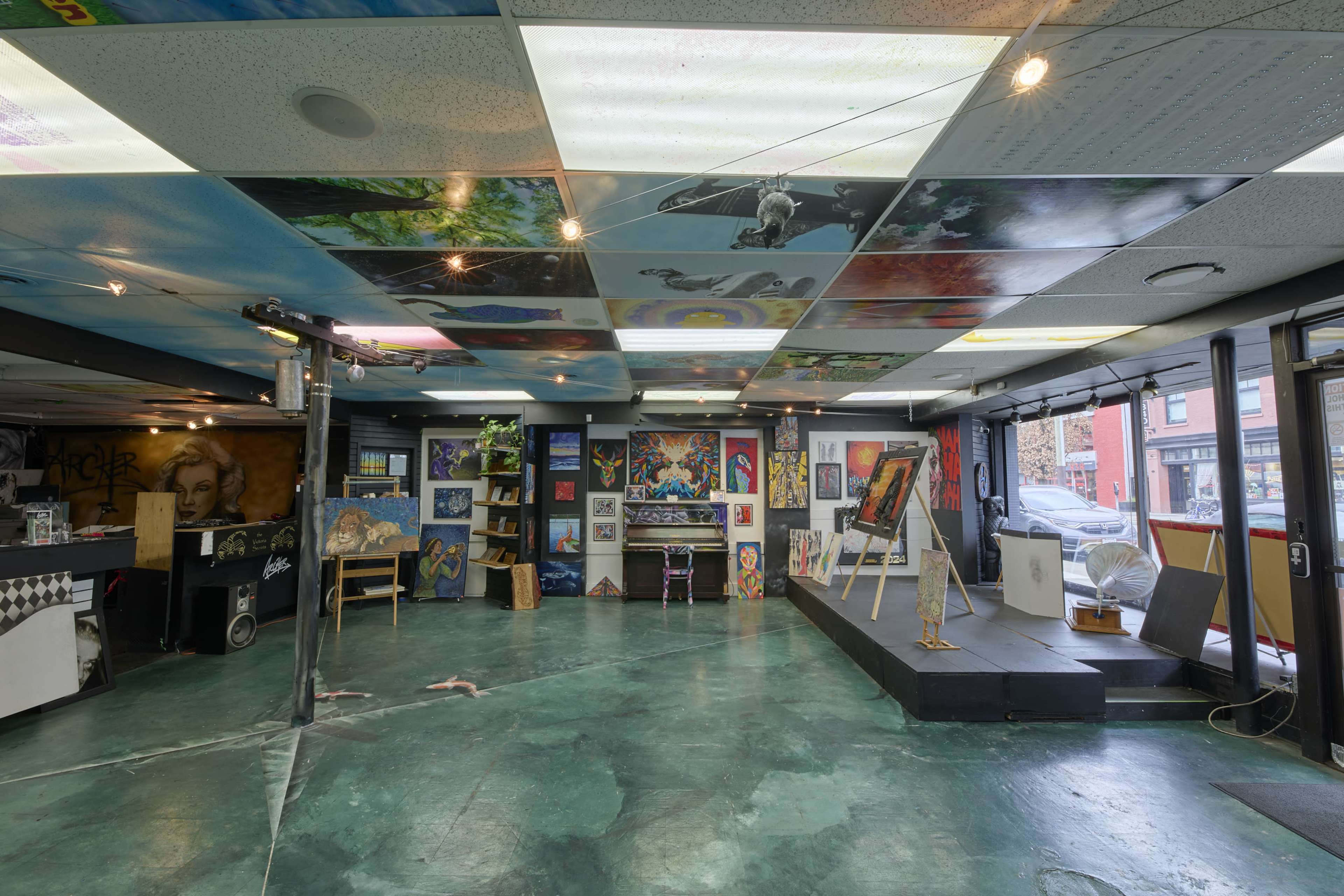 The image shows an art gallery with a variety of paintings displayed on walls and an intricately designed ceiling.