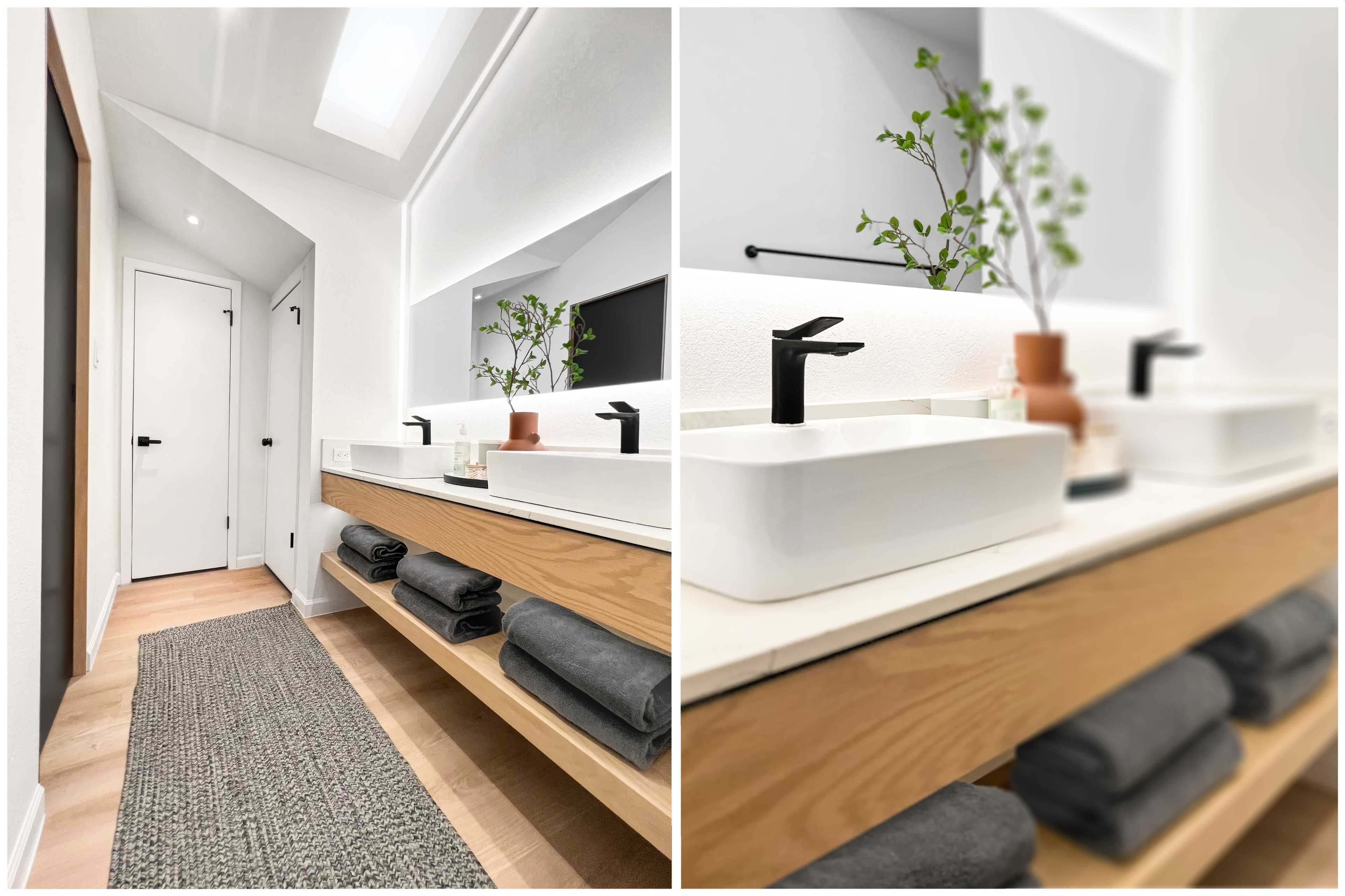 The image shows a modern bathroom with a wooden vanity, white washbasins, and neatly arranged towels on open shelves.