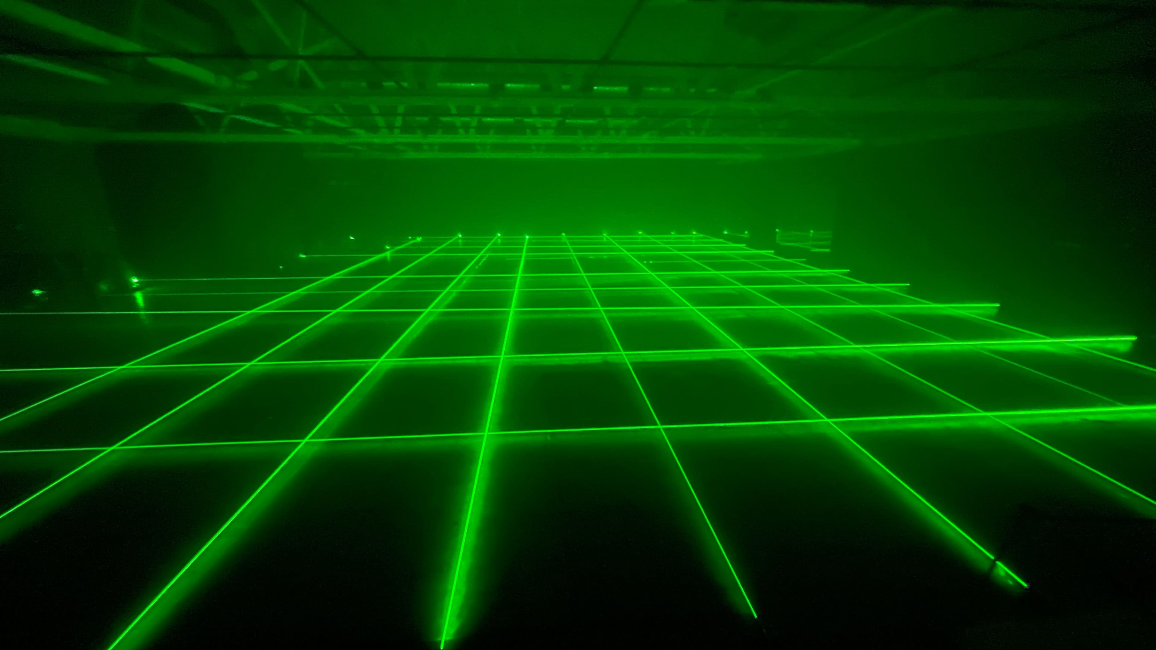 A grid of green laser beams illuminating a dark room.