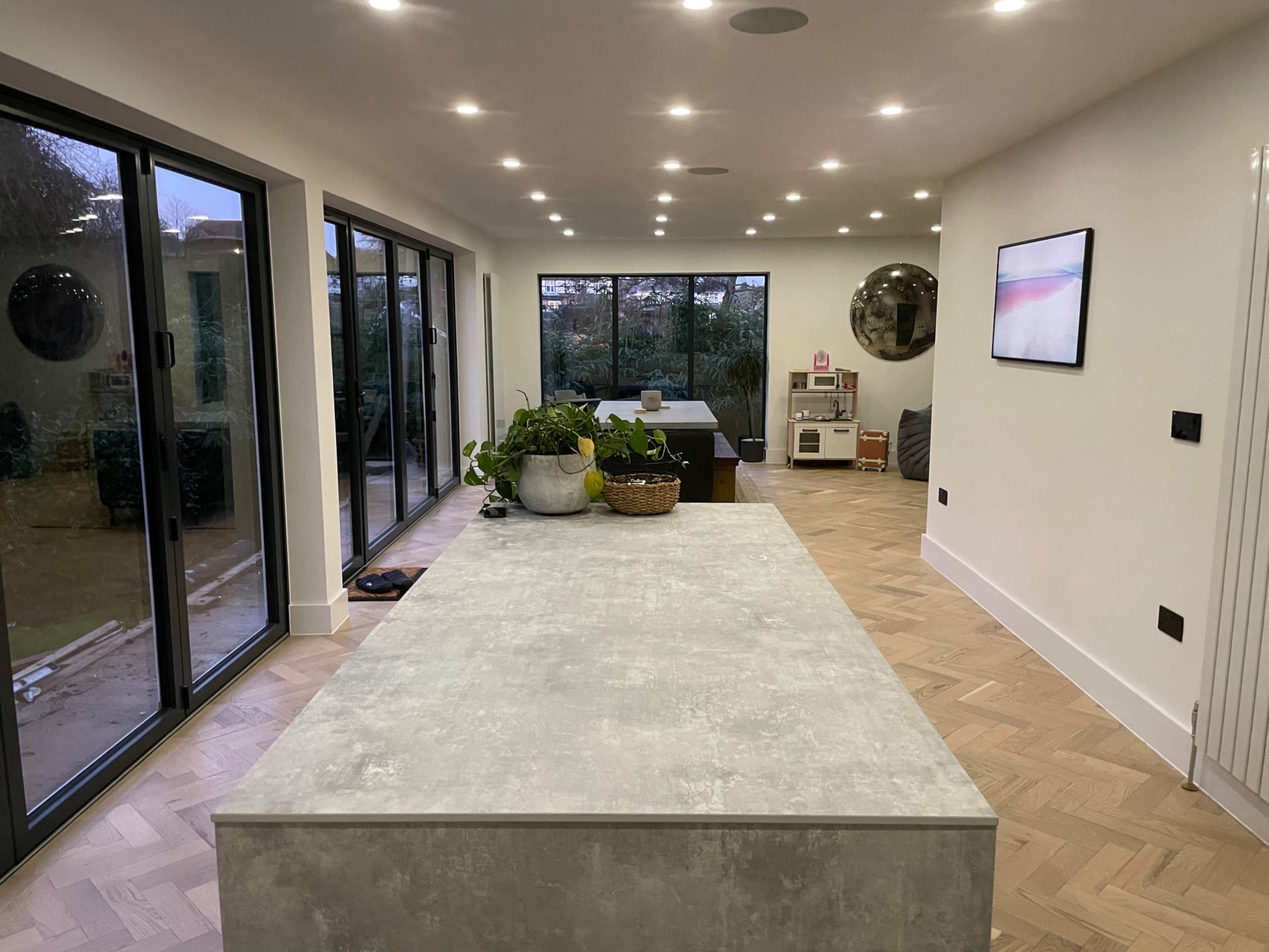 A modern interior with a spacious living area featuring large windows, a central kitchen island, and minimalist decor.