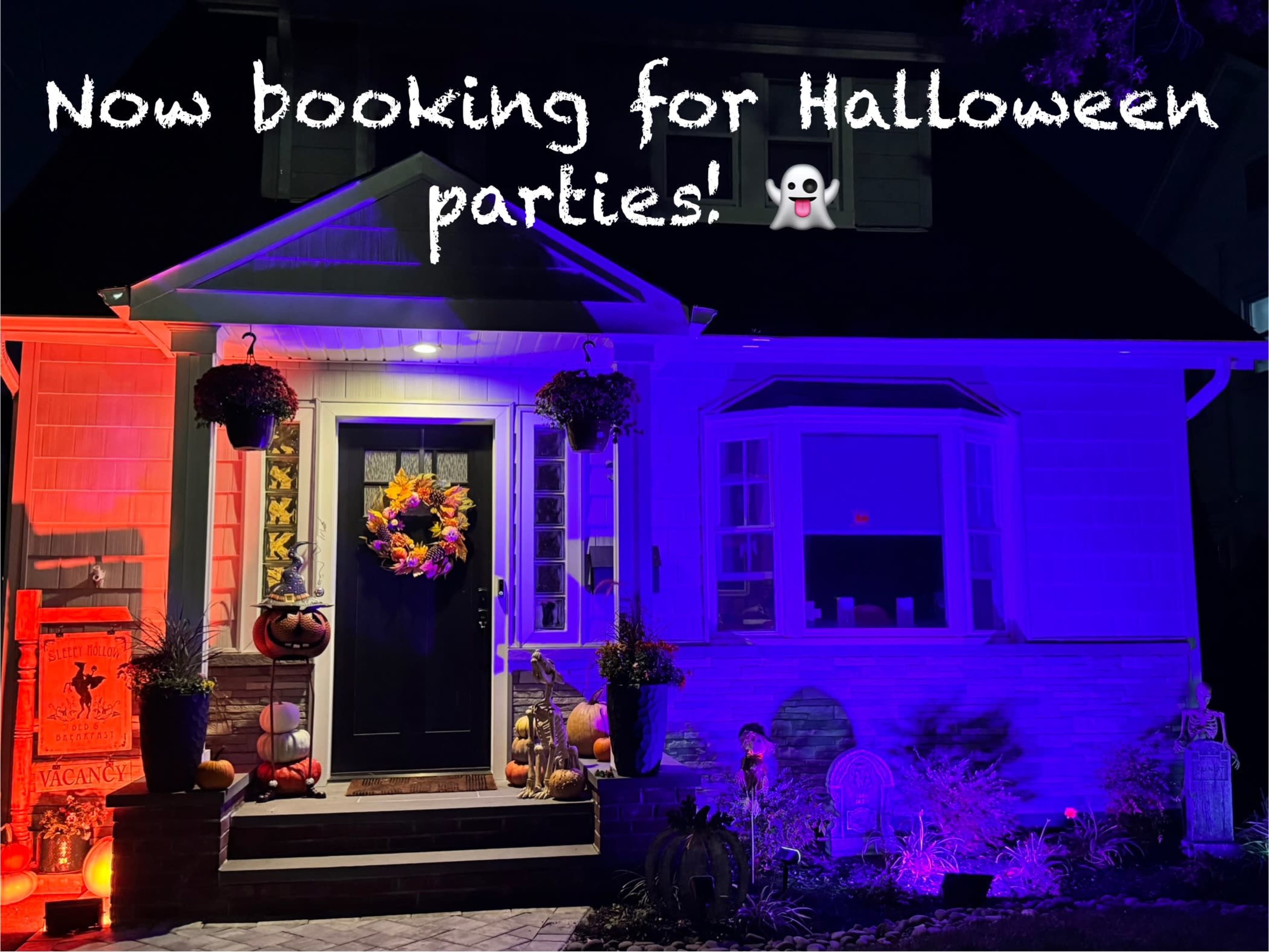 The image shows a decorated house with Halloween-themed decorations, illuminated in purple and blue light, featuring a welcoming front door with a wreath and pumpkins.