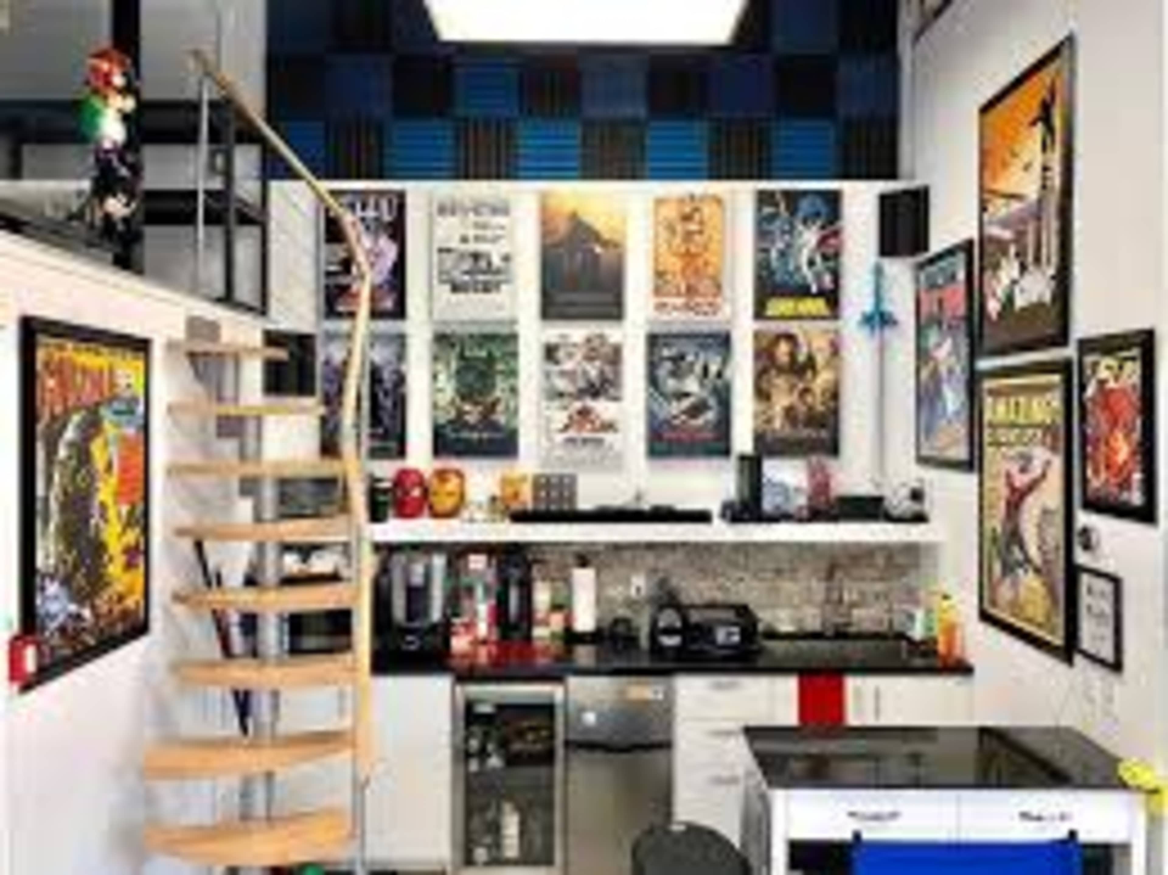 A modern home office features a spiral staircase, a kitchenette with appliances, and a wall decorated with various movie and pop culture posters.