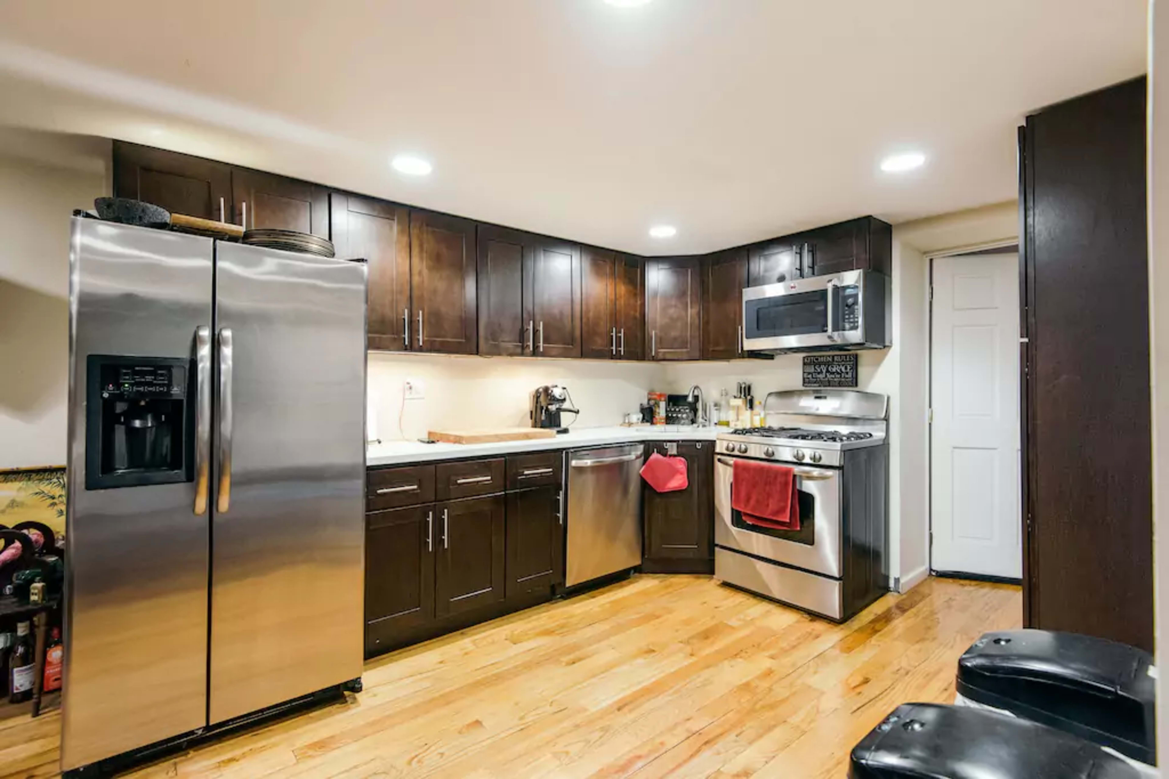A kitchen featuring stainless steel appliances, dark wood cabinetry, and a wooden floor.