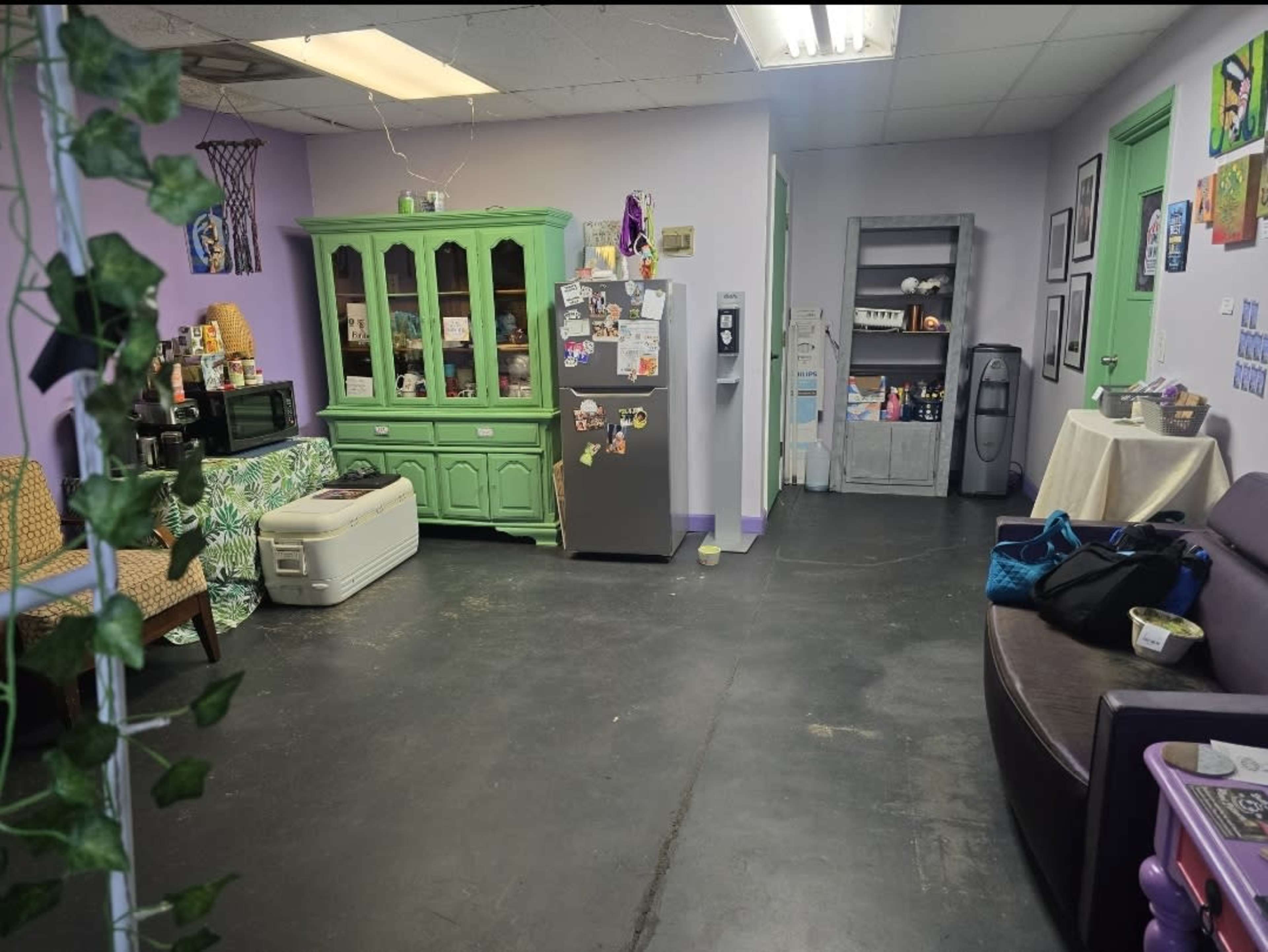 A brightly colored room with green furniture, a refrigerator, and a mix of seating areas.